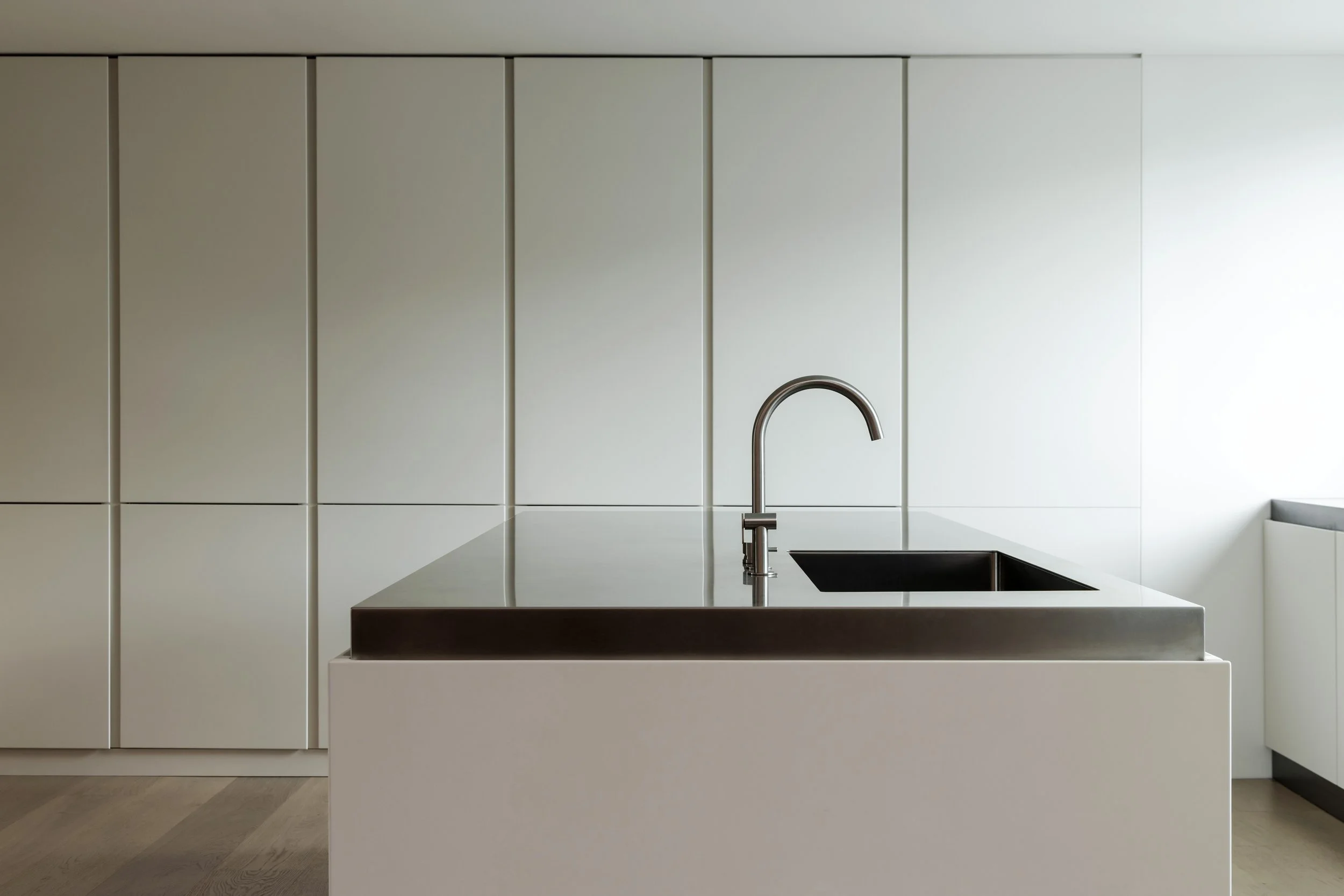 Modern kitchen with white cabinetry and a black sink.