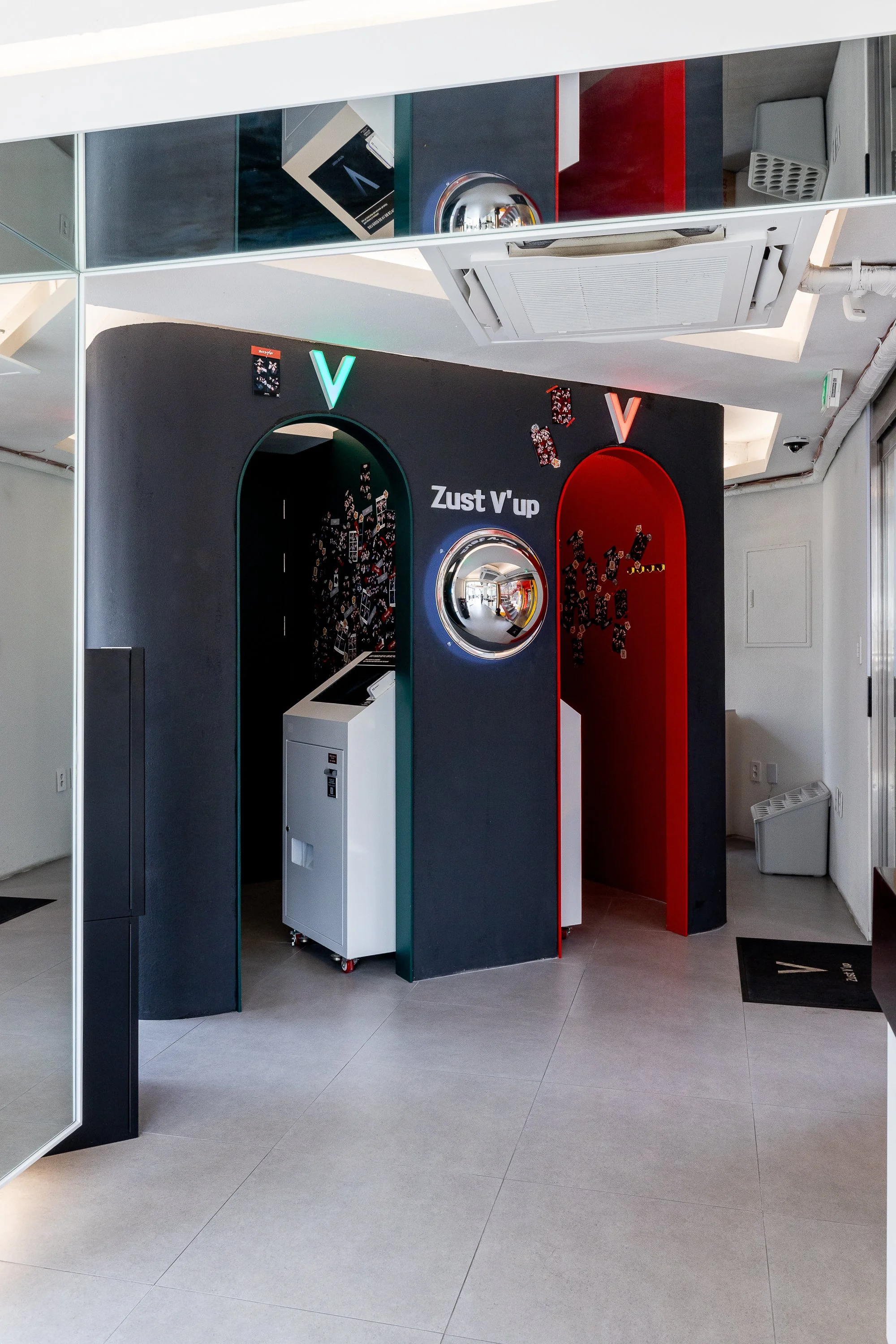 A modern, minimalist arcade game station called 'Zust V'up' with two distinct sections, one green and one red, each featuring an arcade screen and a mirror at the center, and surrounded by playing cards.
