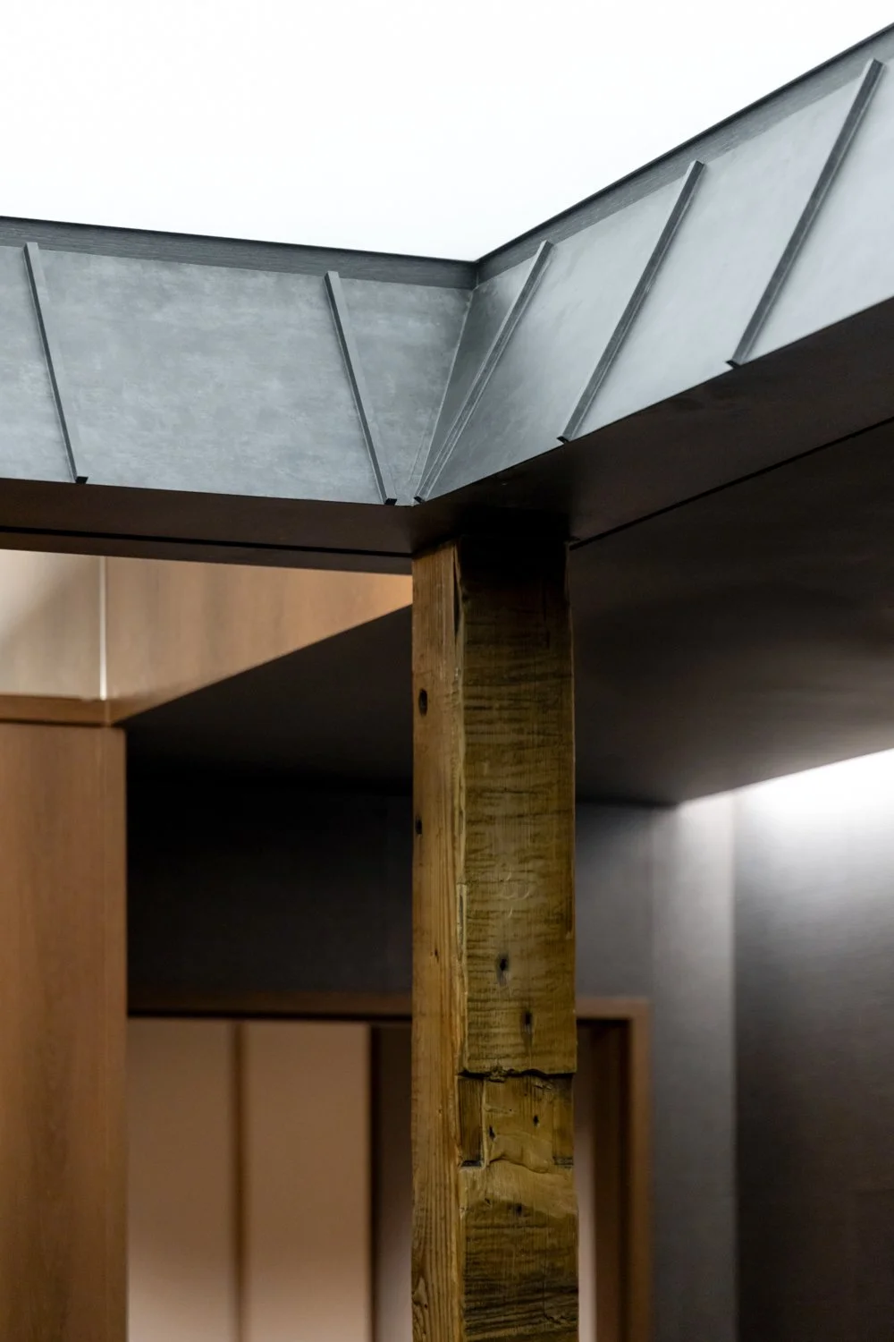 Close-up of a corner of a modern table with a metal top and wooden legs.