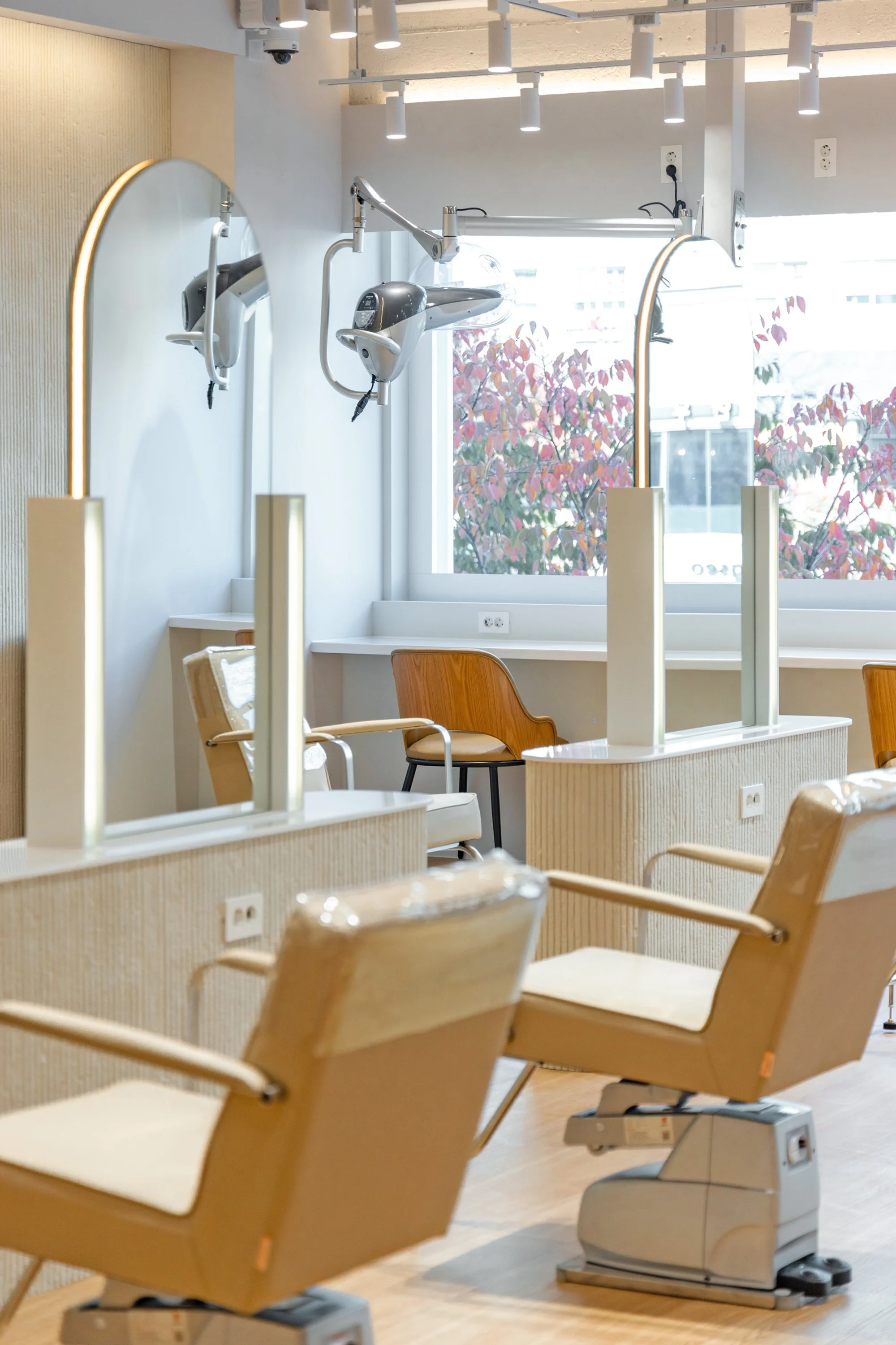 Empty hair salon with chairs, mirrors, and hair dryers in a modern, well-lit space.