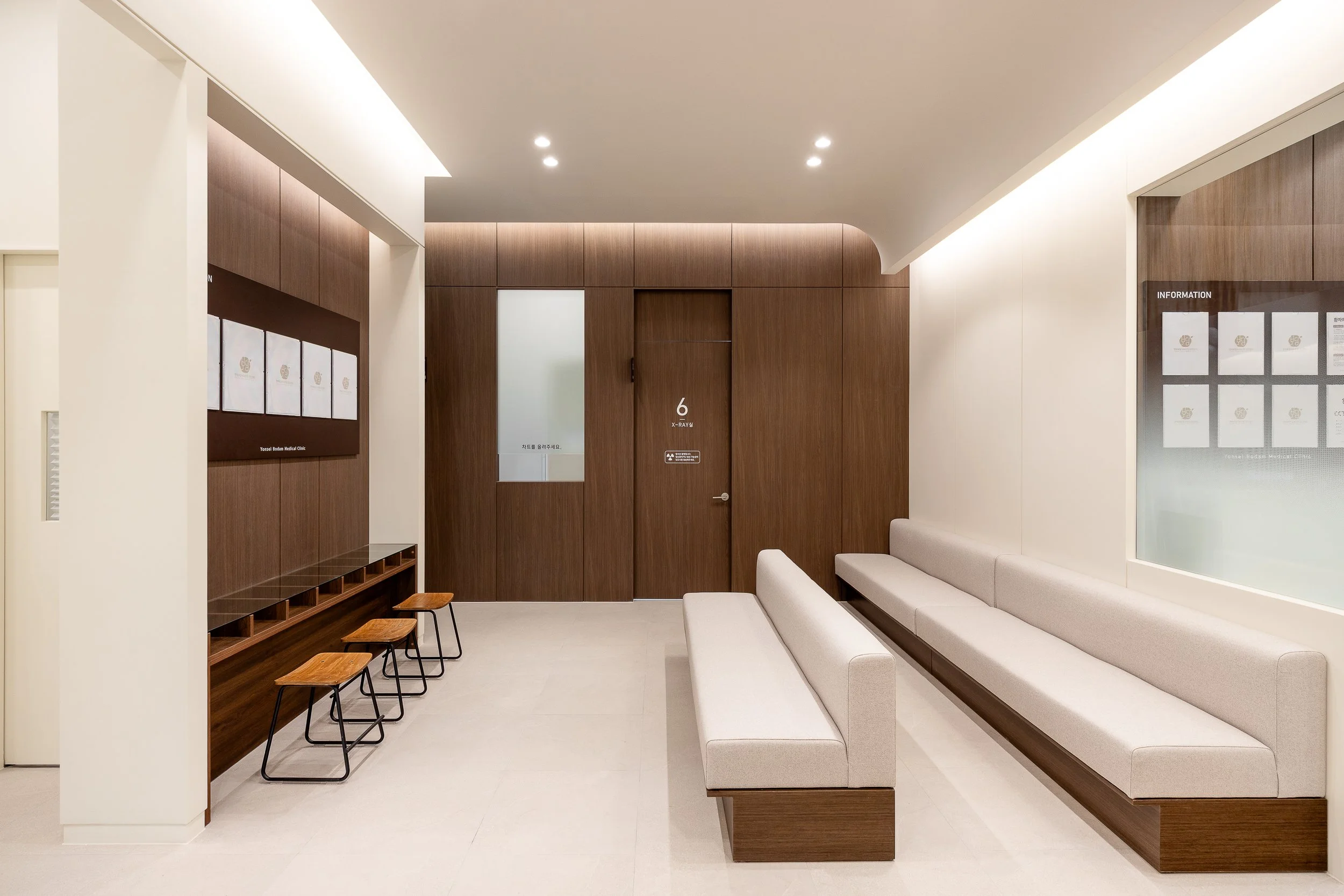 Empty waiting room with beige benches, wooden wall paneling, and informational display boards