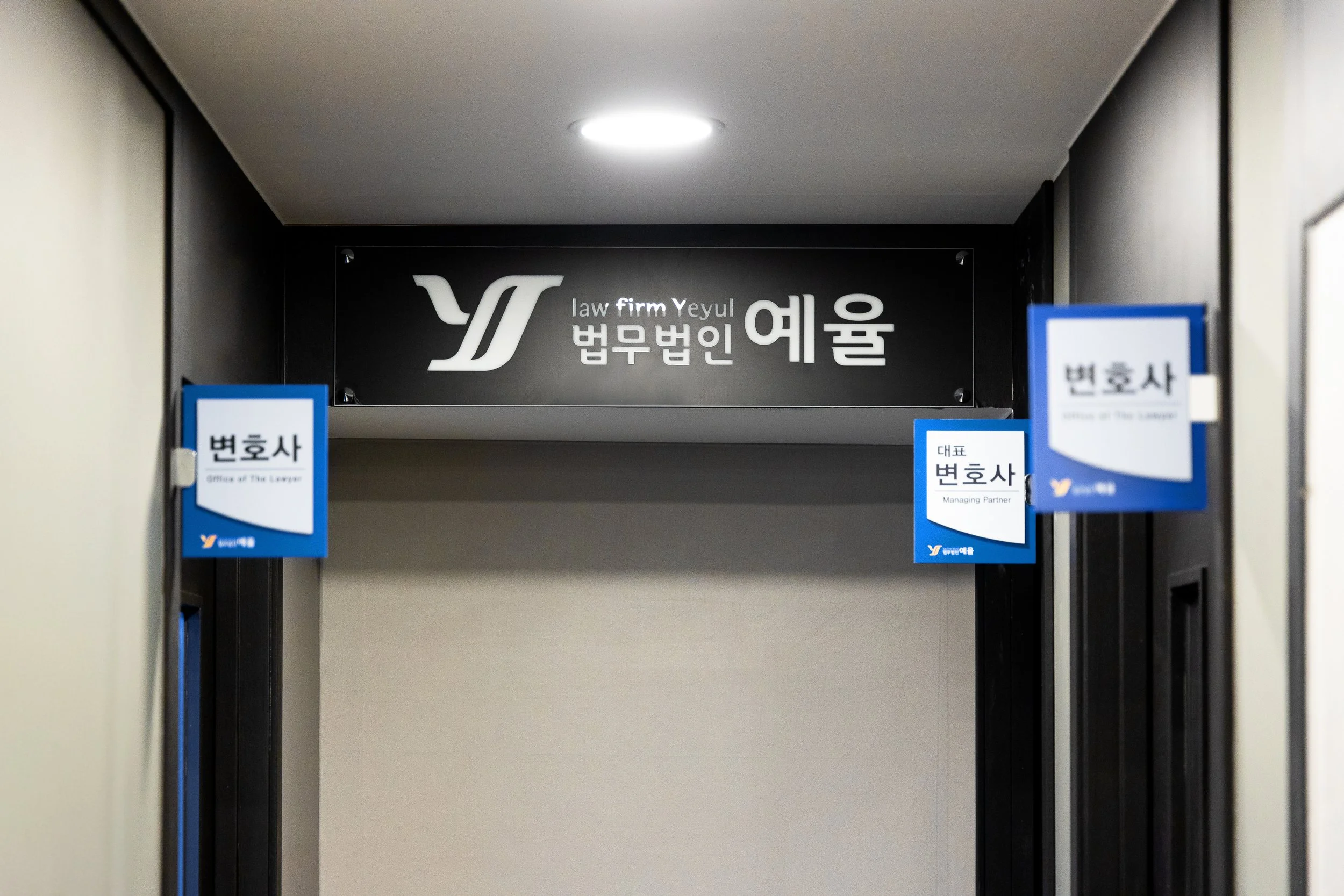 Sign for a law firm named Yeyul on a black background, with additional signs indicating lawyers and managing partners on either side.