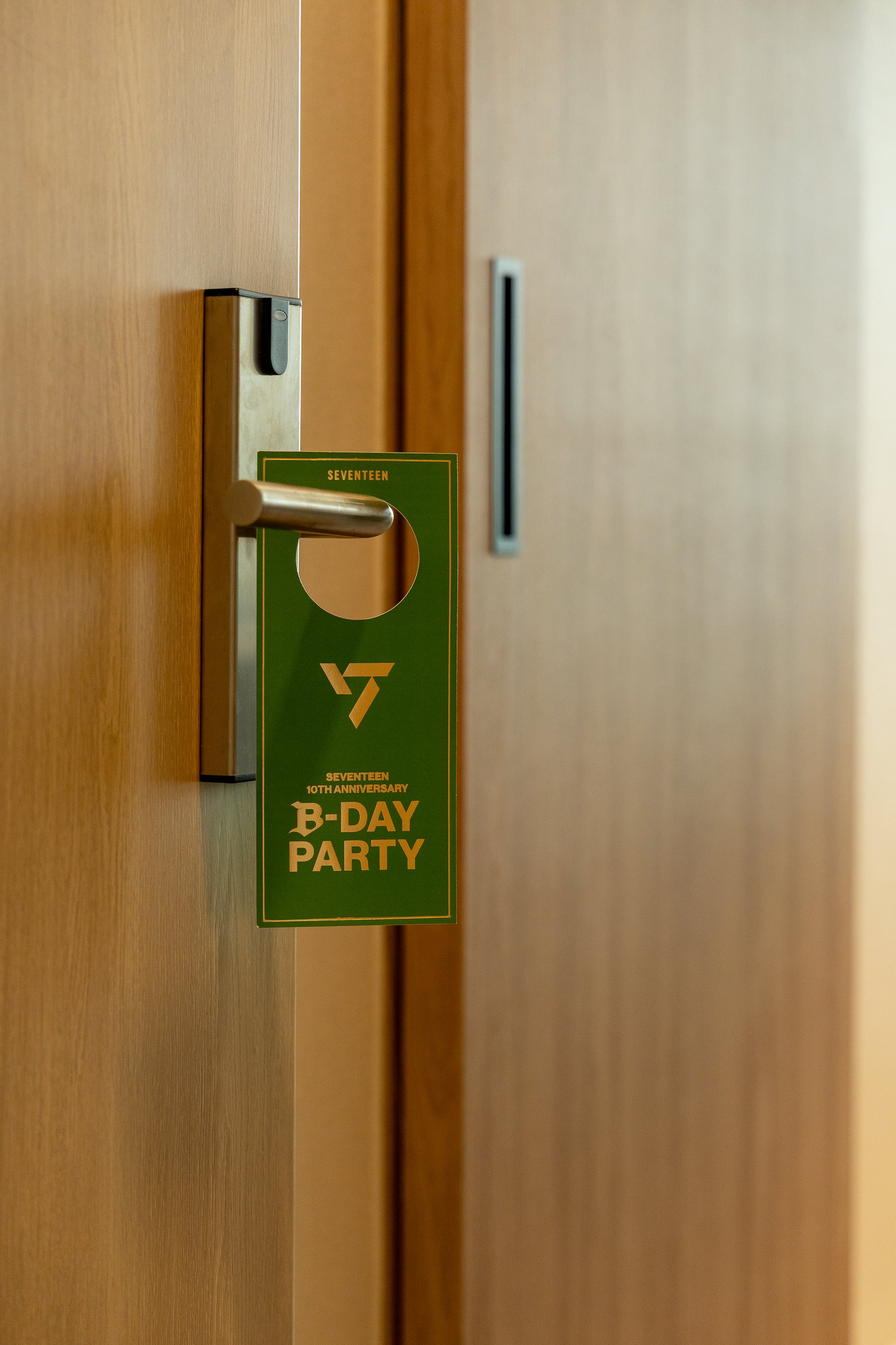 Door with a green hanging sign that reads 'SEVENTEEN 10TH ANNIVERSARY B-DAY PARTY'.