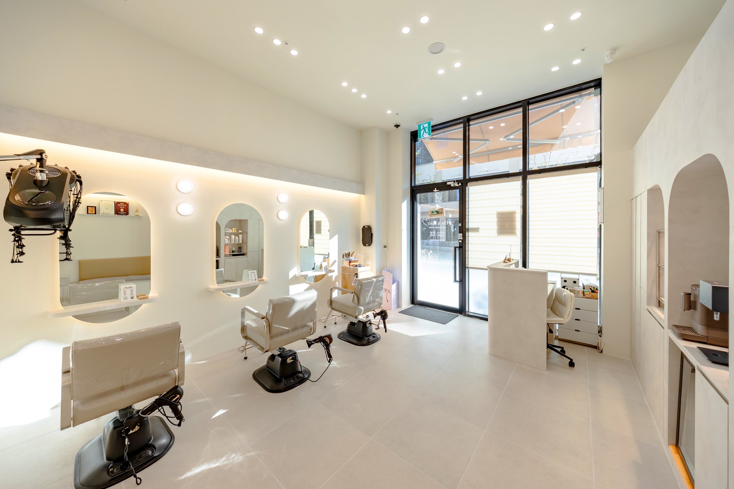 Clean, modern hair salon with three styling stations and large glass front door.