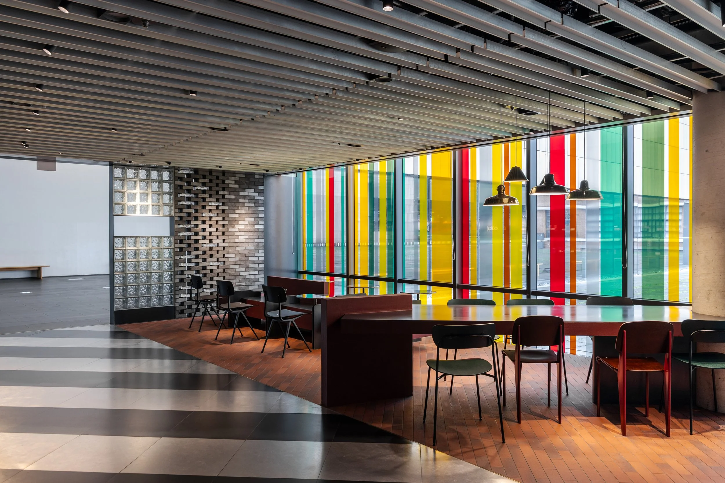 Modern indoor space with a colorful glass wall, tables, and chairs