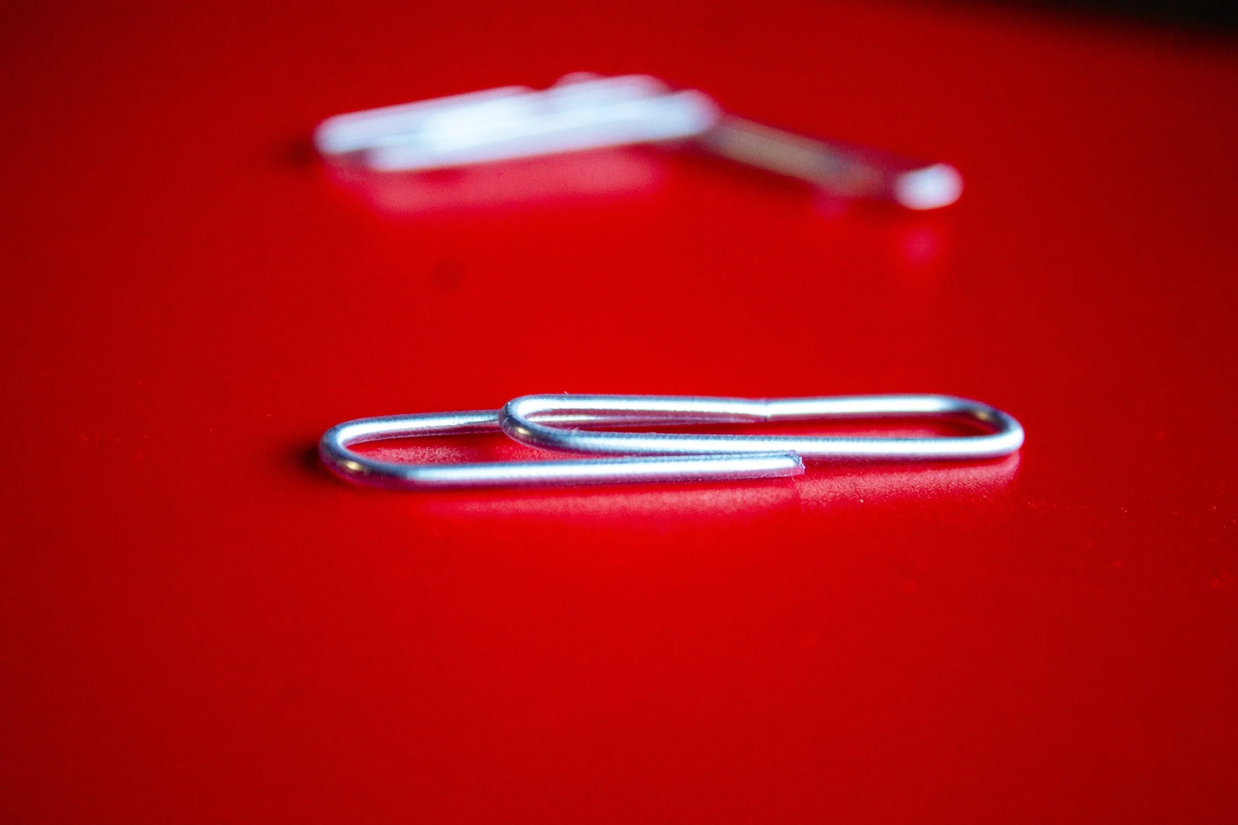 Close-up of paperclips on a red surface with a shallow depth of field