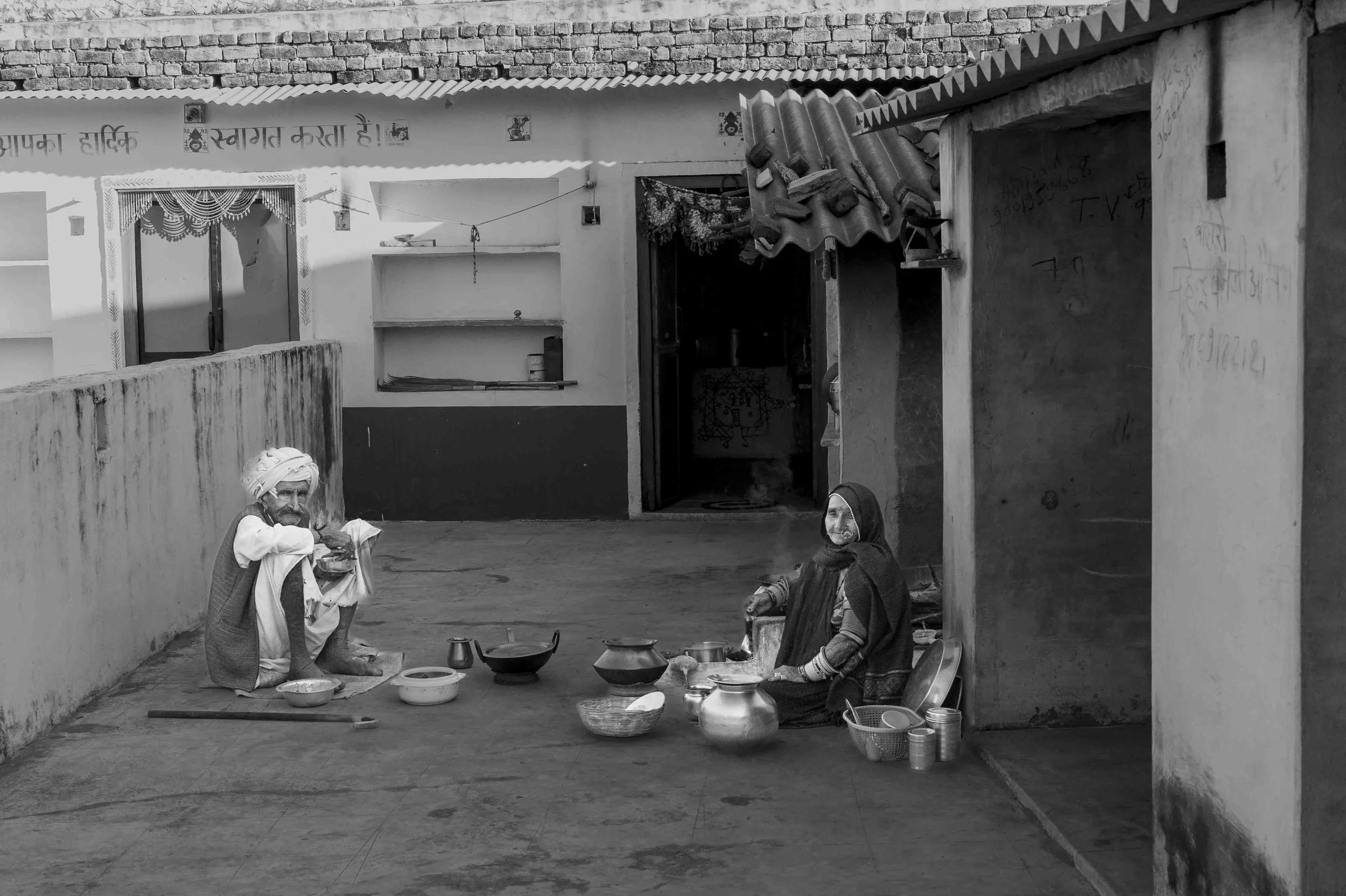 This Rabari couple eats a traditional breakfast in their courtyard, with bread and other dishes cooked over a wood  stove.