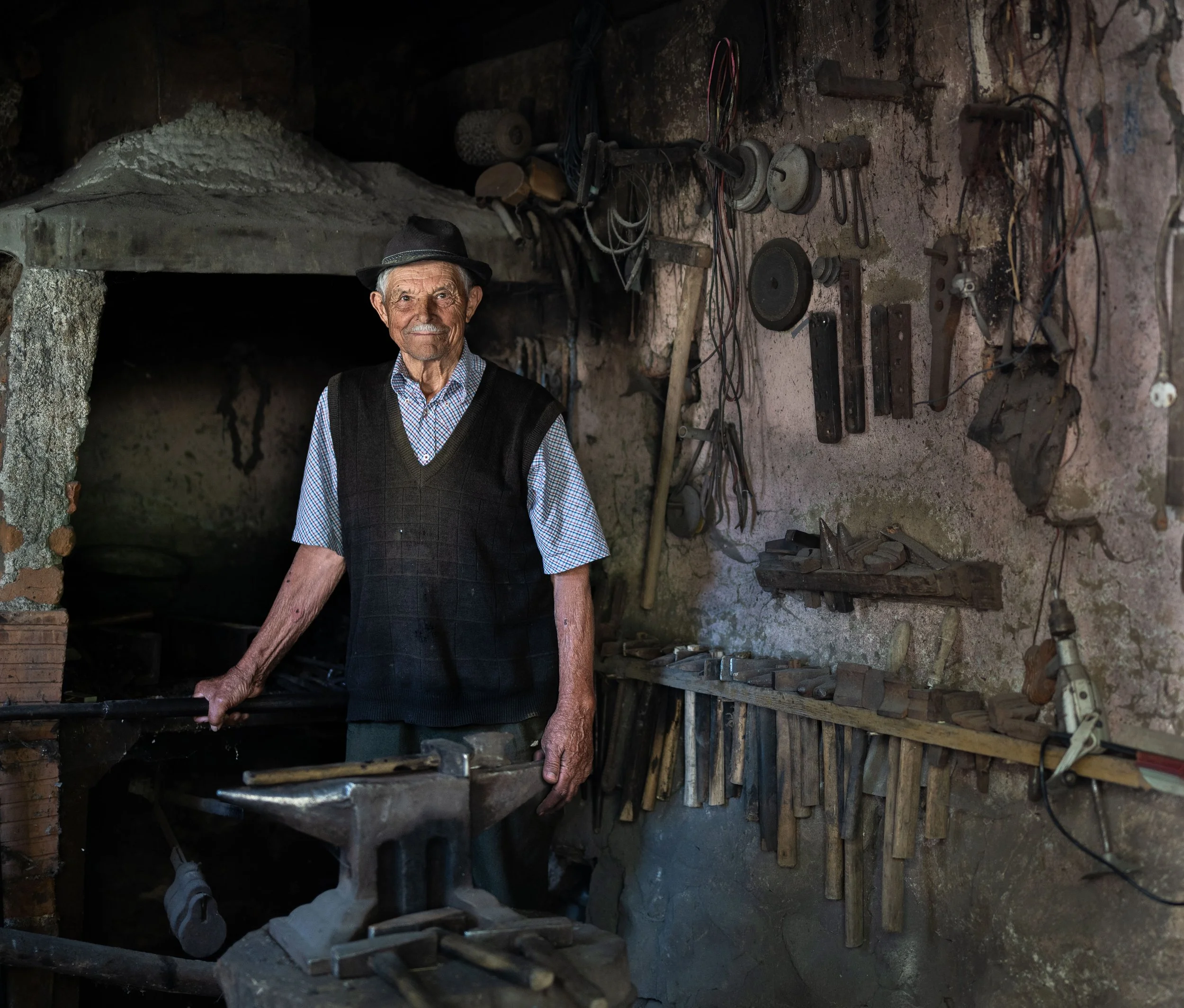 Mr. Bogdan, a recently retired blacksmith (the last in his small village), is posing in his shop. 