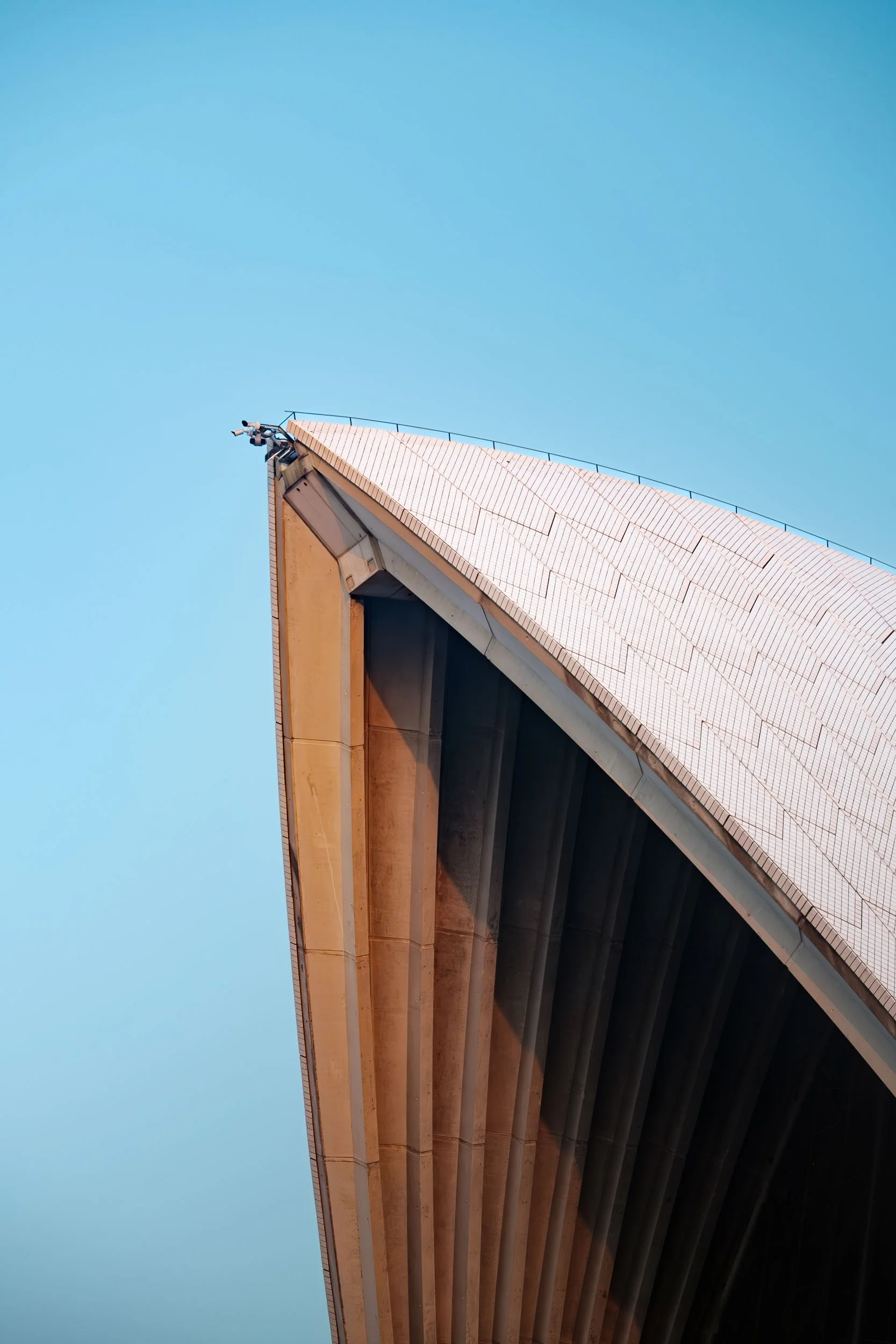Close-up of Sydney Opera House roof with blue sky in the background.