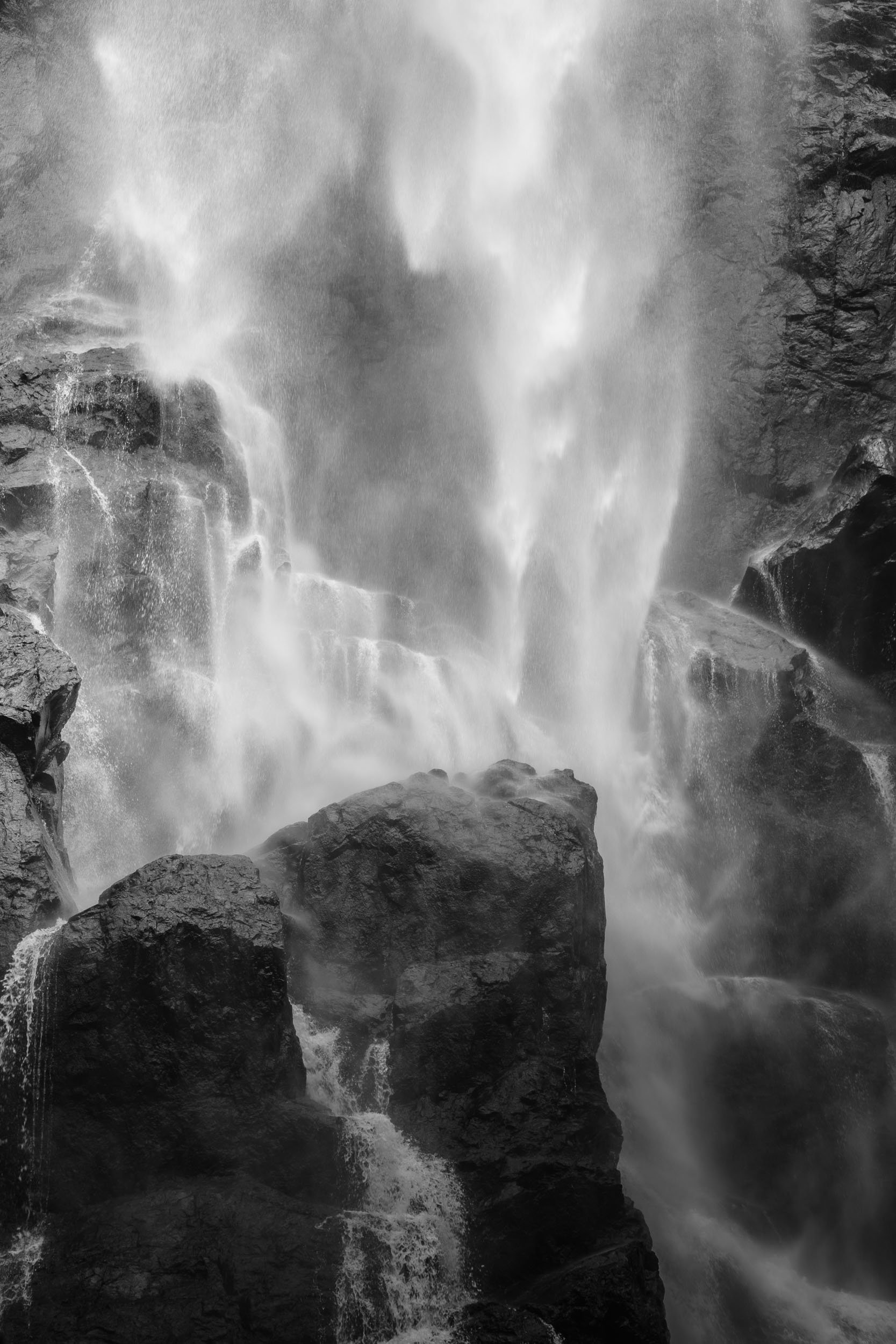 Black and white image of a powerful waterfall cascading over rocks.