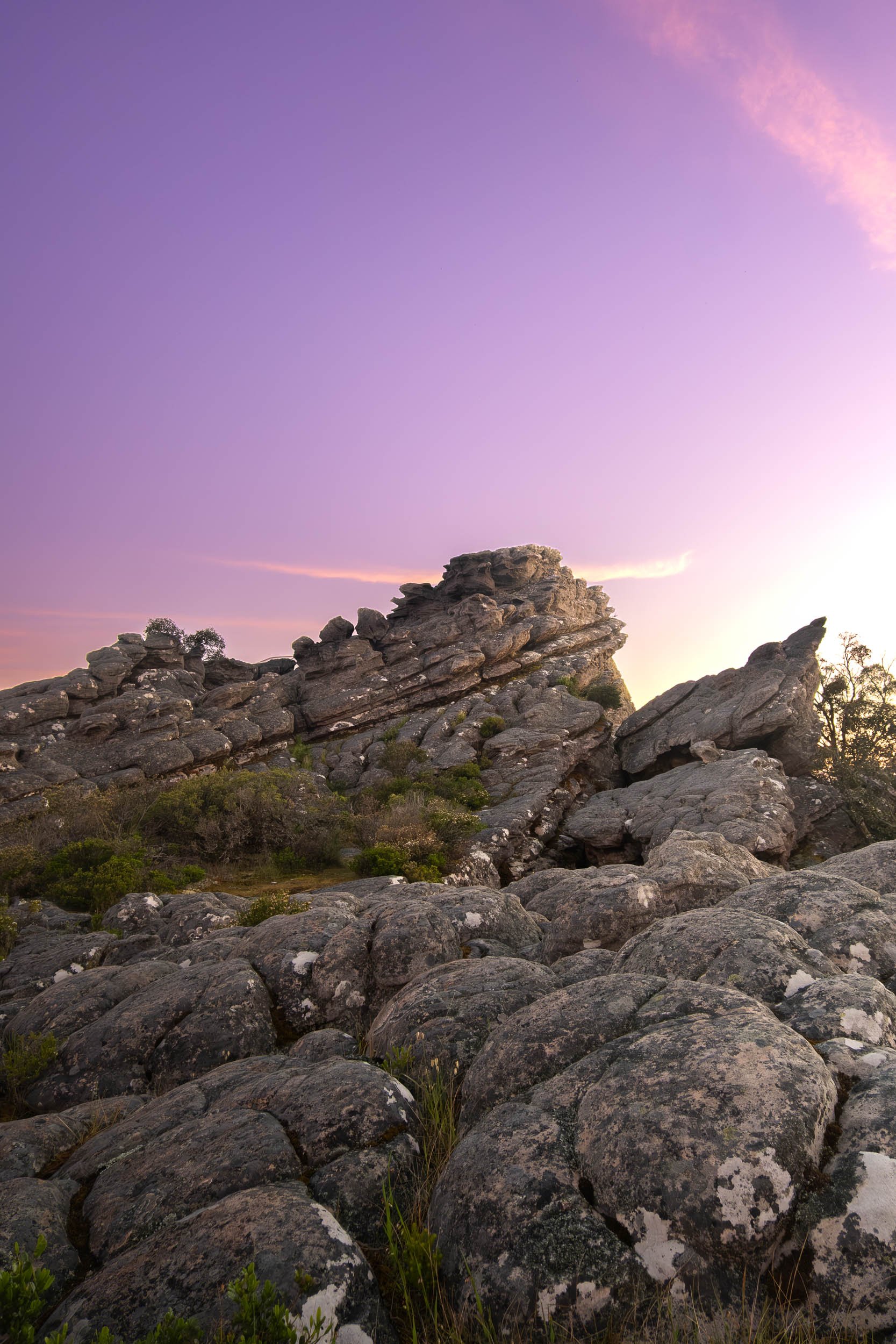 Rock formation at sunset with purple sky and pink clouds.