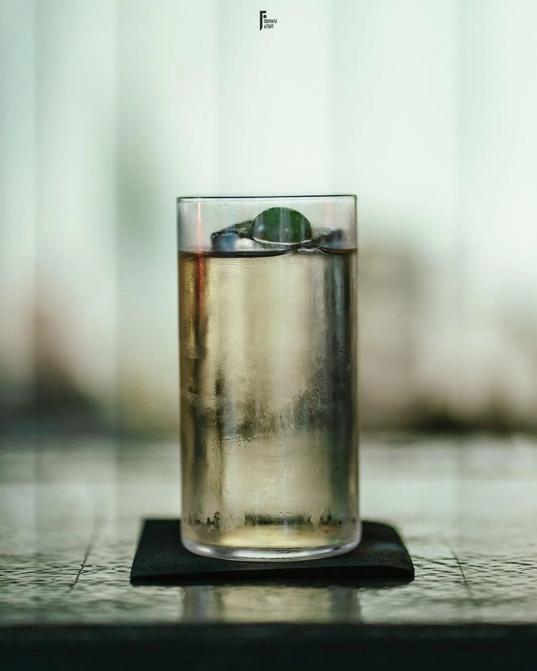 Minimalist highball cocktail with ice and citrus garnish, crafted by mixologist David Paz, presented in a refined bar setting.