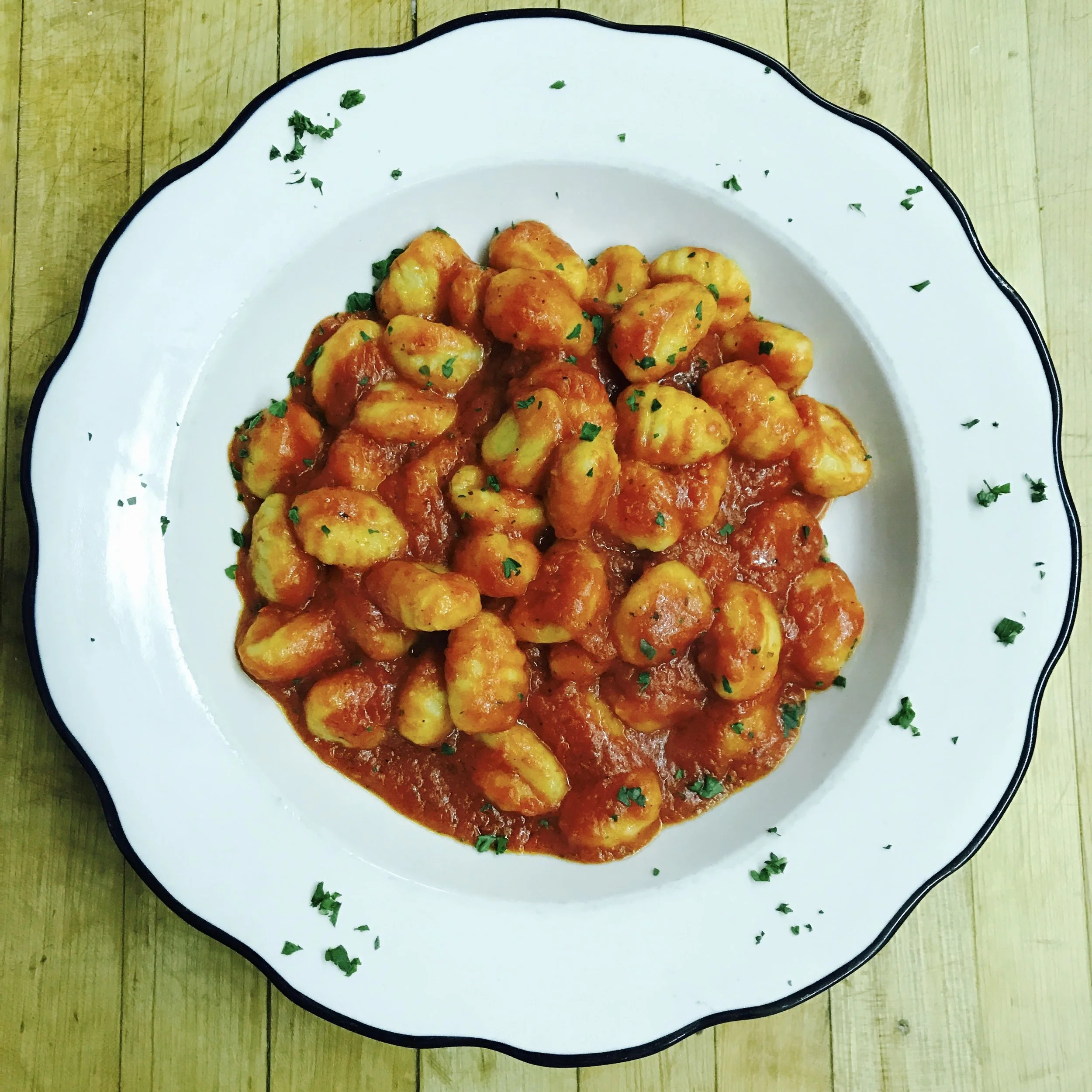 Plate of gnocchi with tomato sauce garnished with chopped parsley
