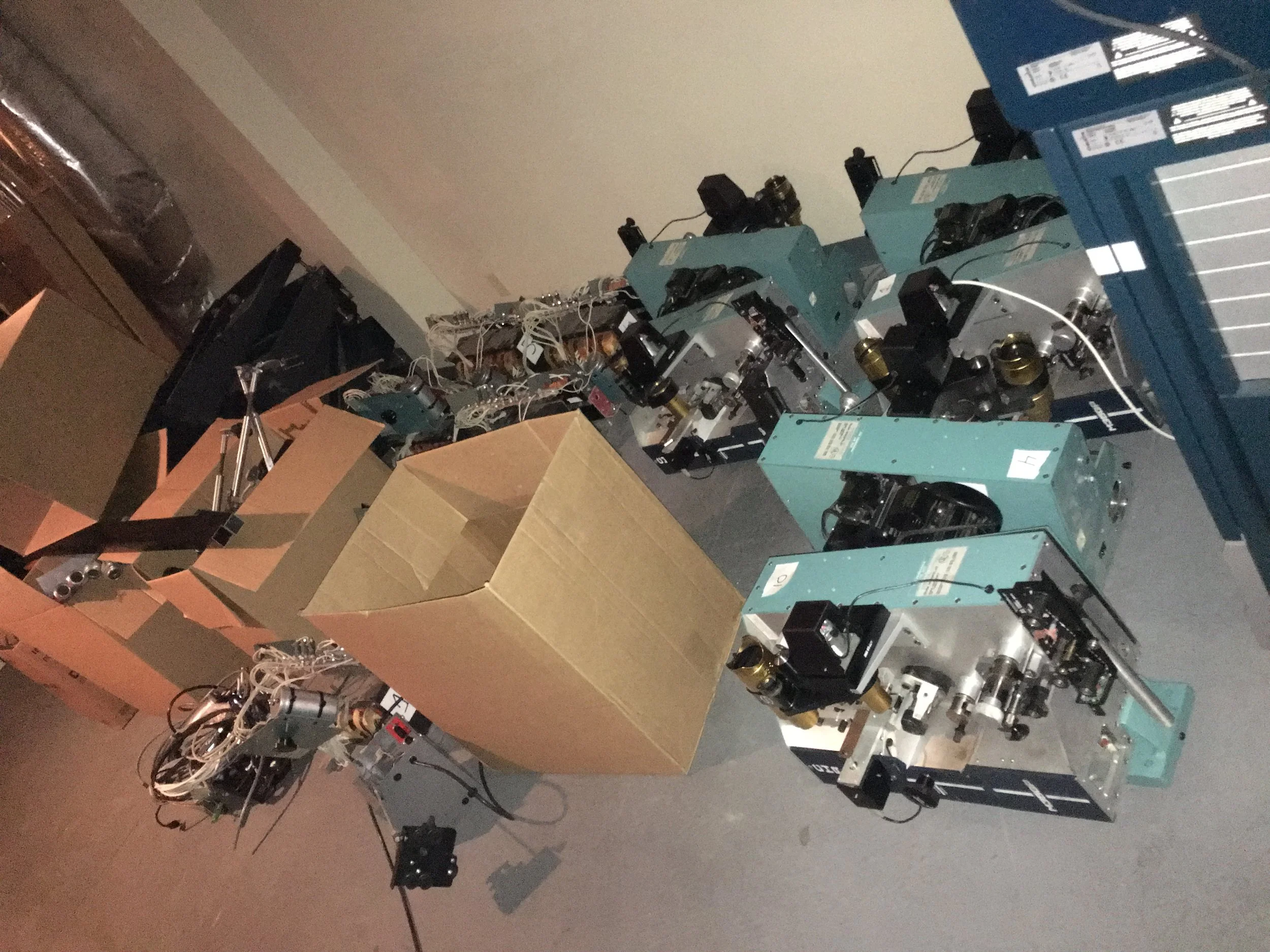 Multiple microscopy machines and a cardboard box in a room.