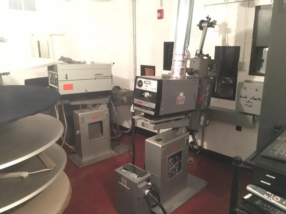 Laboratory equipment, including a microscope, a laser, and control panels, on a red floor in a lab setting.