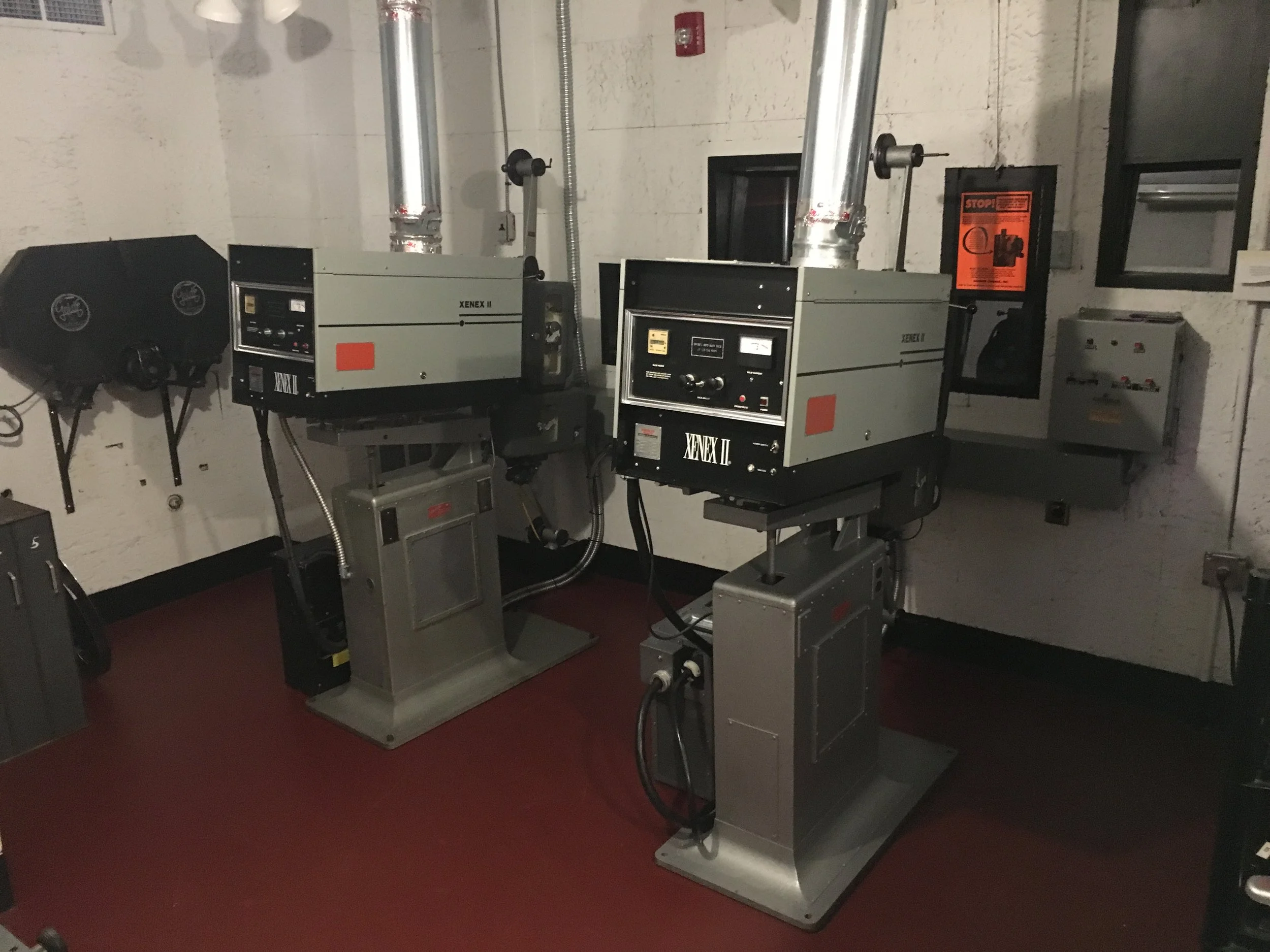 Two industrial X-ray machines used for non-destructive testing in a lab, with control panels and ventilation ducts overhead.