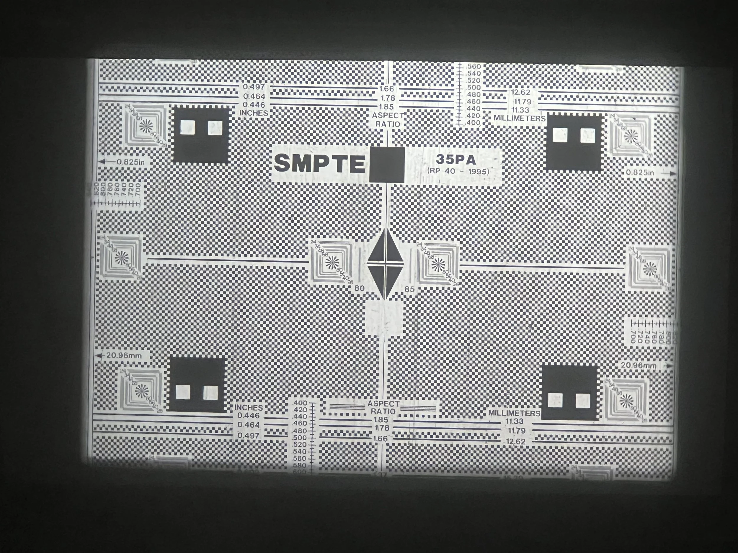 A grayscale test pattern with various measurement scales, labels, and geometric patterns used for calibration of screens or cameras.