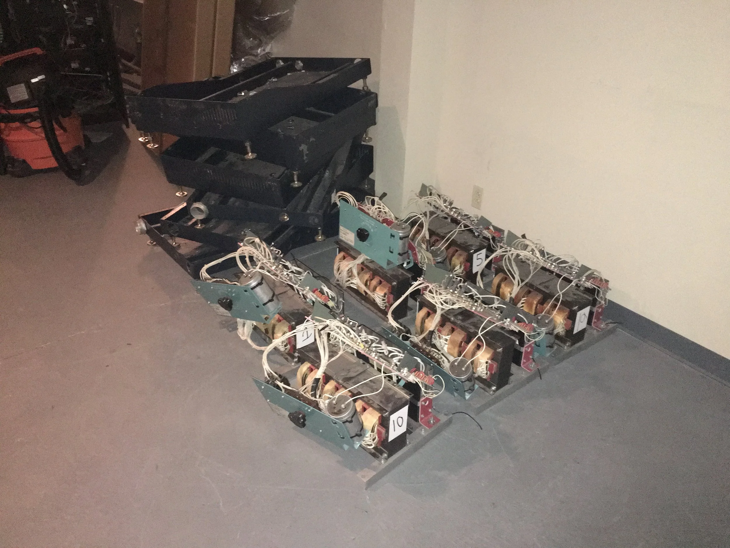 Disassembled mechanical or electronic device with multiple circuit boards, wires, and components laid out on the floor.