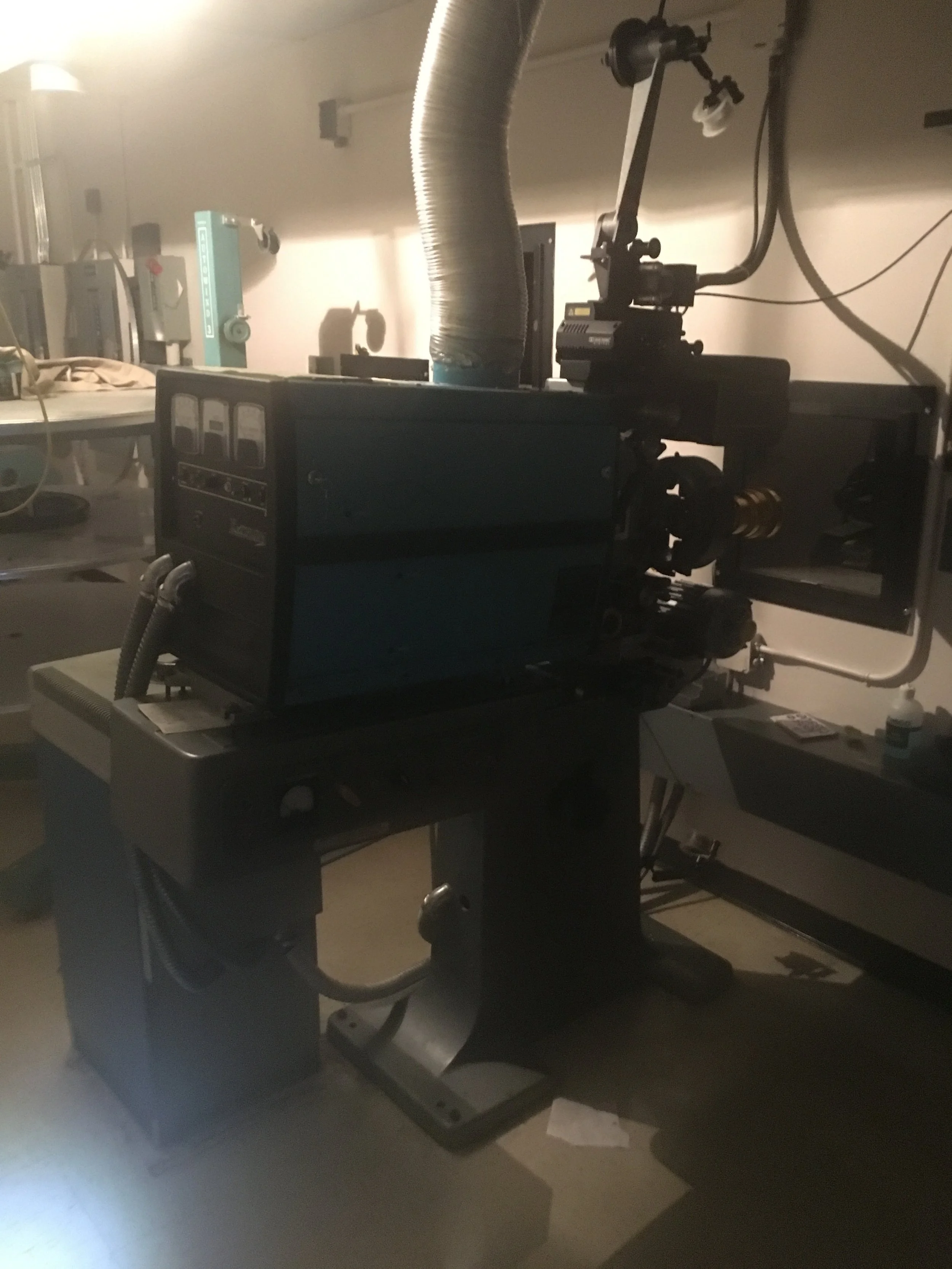 A scientific microscope setup on a workbench in a laboratory setting, with various equipment and supplies around.