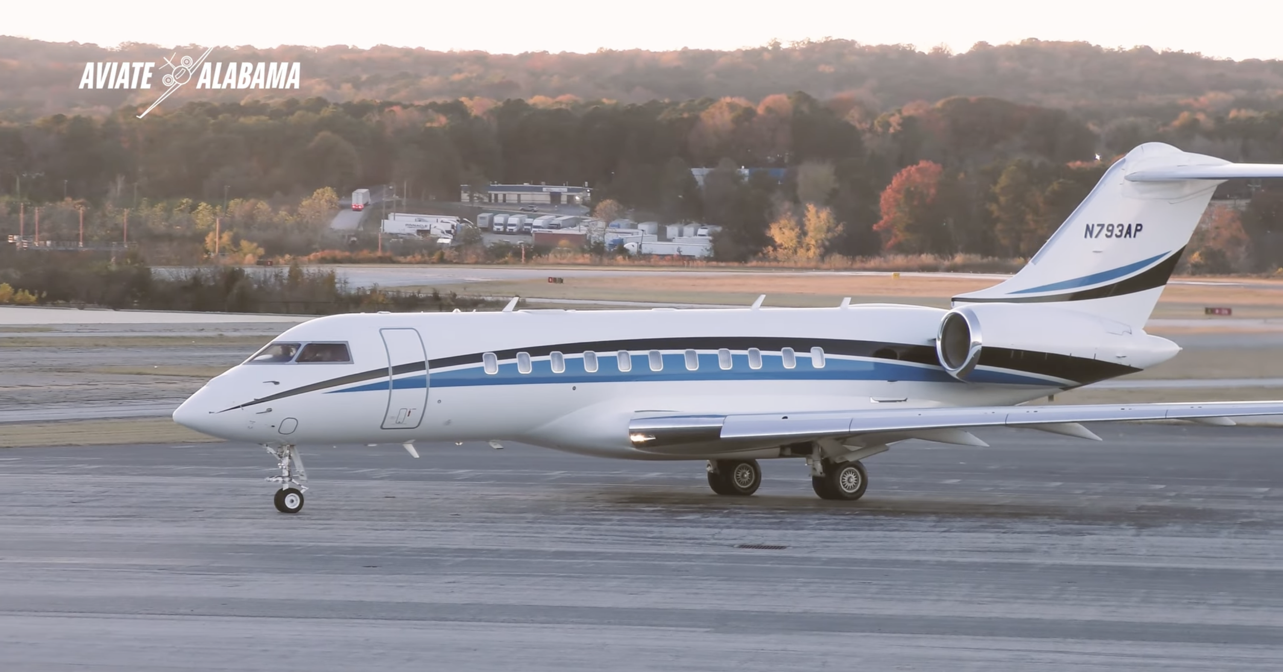 Private jet on airport runway with trees in the background and a 'Aviate Alabama' logo in the top left corner.