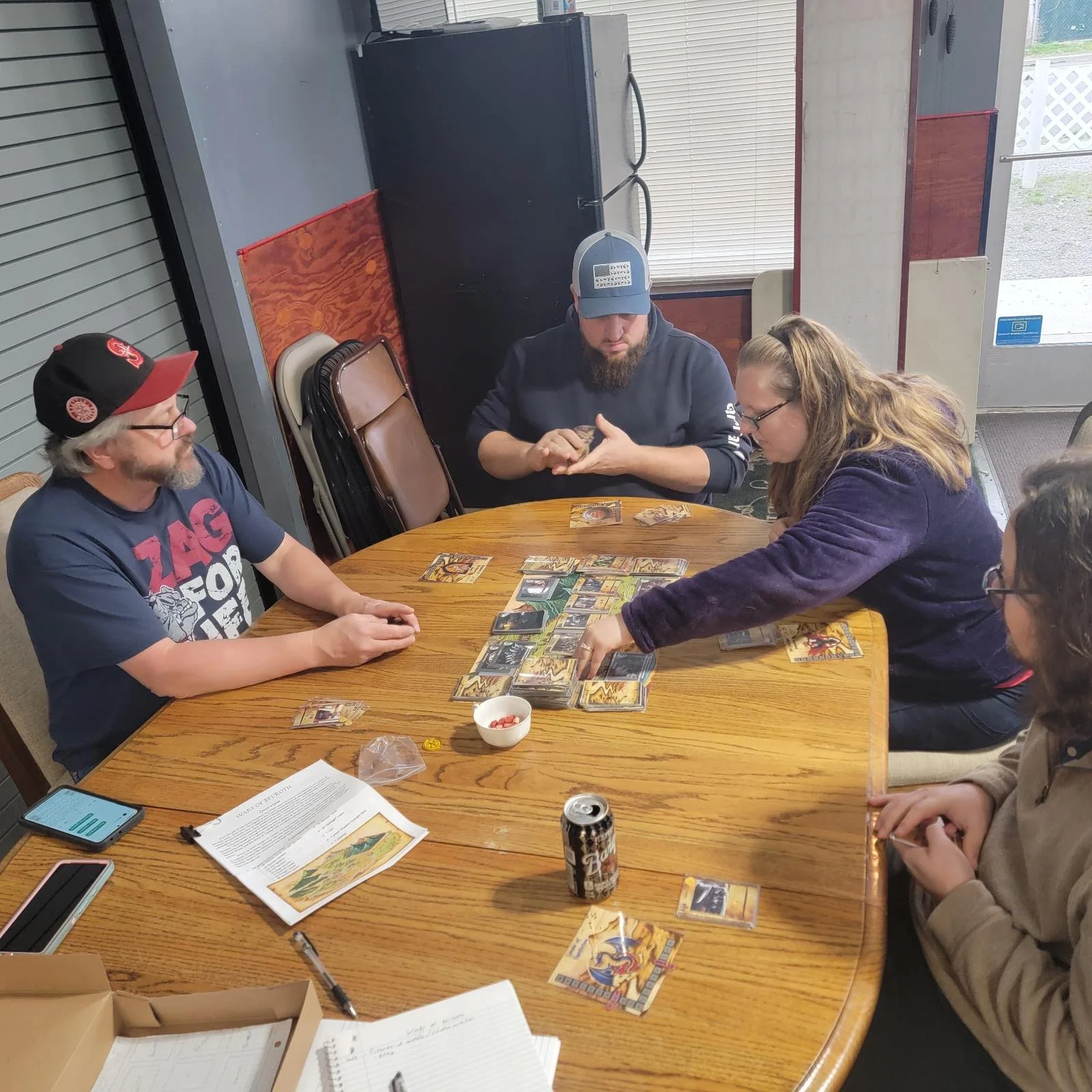 A group of people watching a game of Tides of War being played 