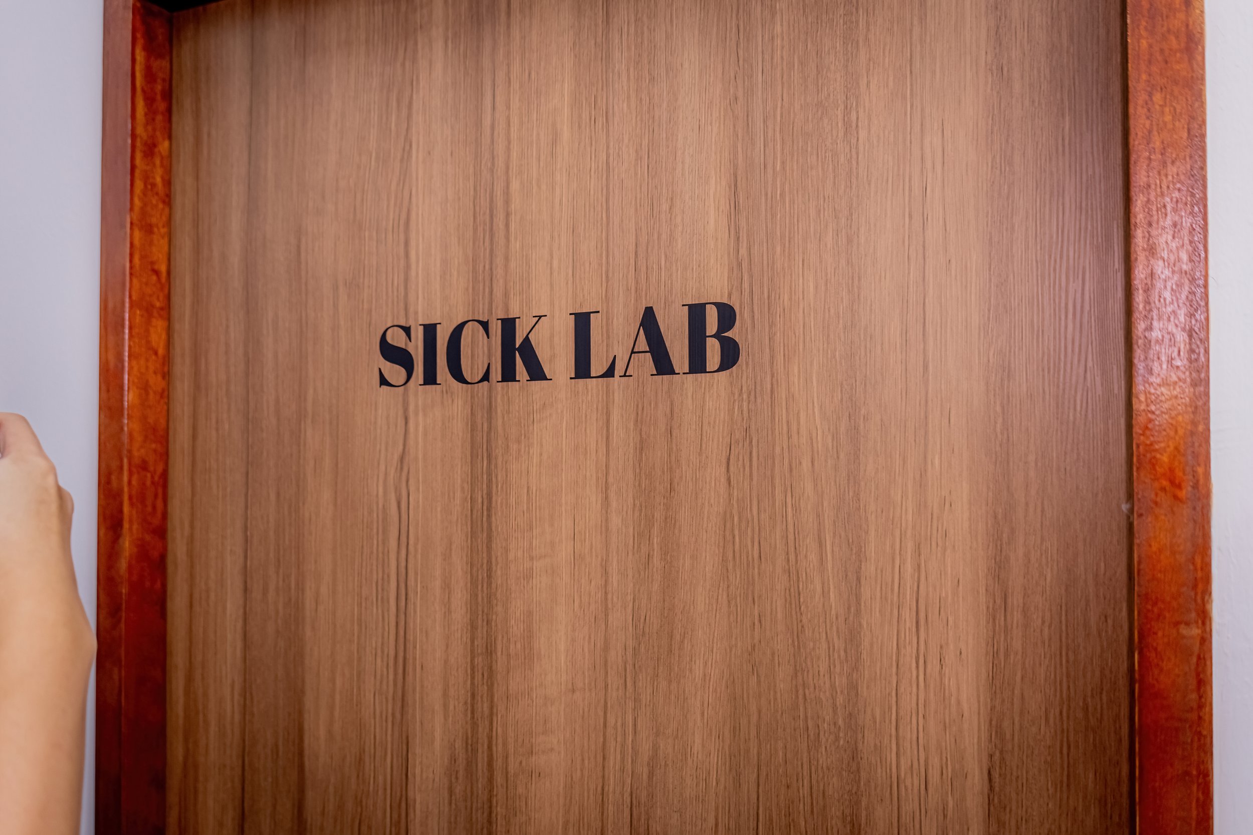 Wooden door with the words 'SICK LAB' printed on it in black text.
