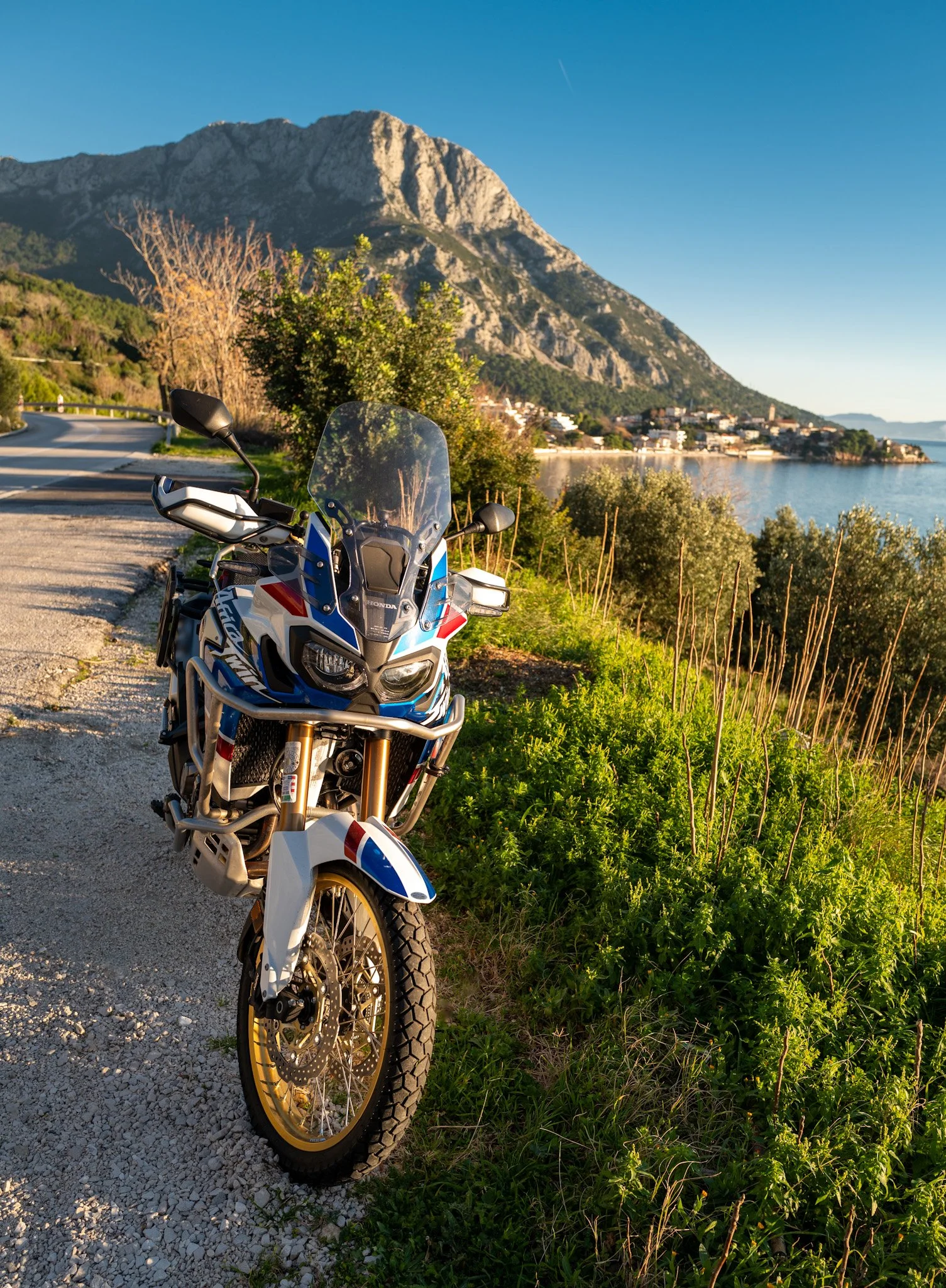 Africa Twin motorcycle parked on a scenic Adriatic coastal road in Croatia during a guided motorcycle tour.