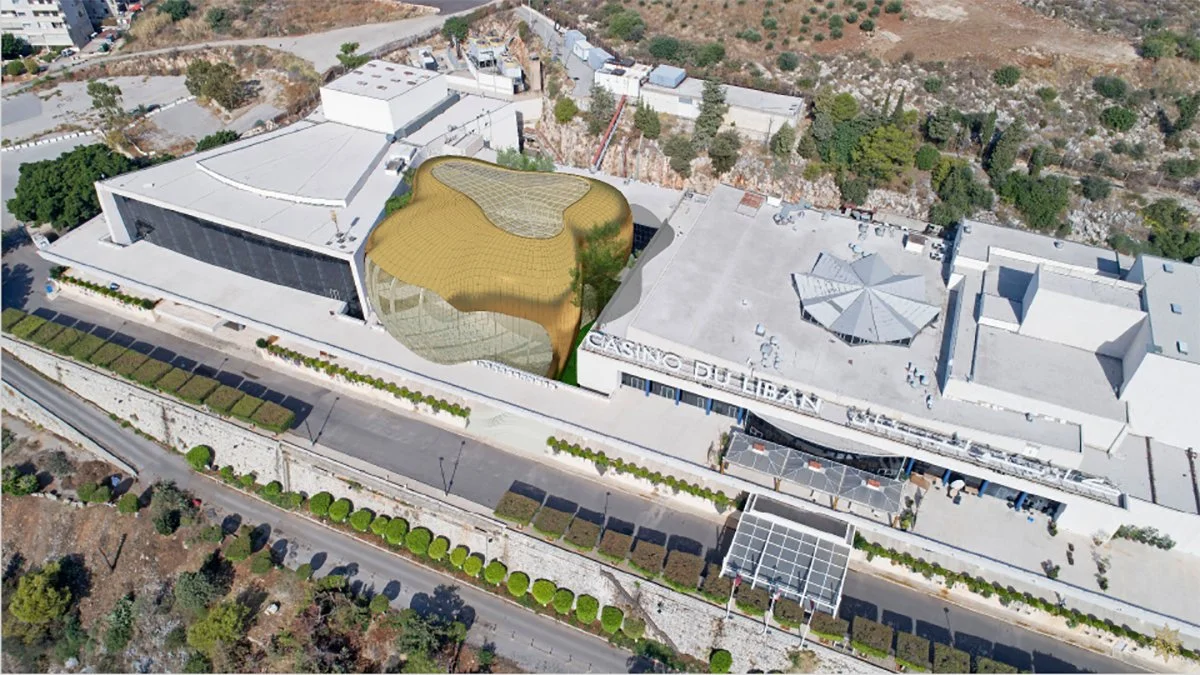 Aerial view of Casino D'Alban with a distinctive golden, organic-shaped roof, surrounded by white buildings and greenery.