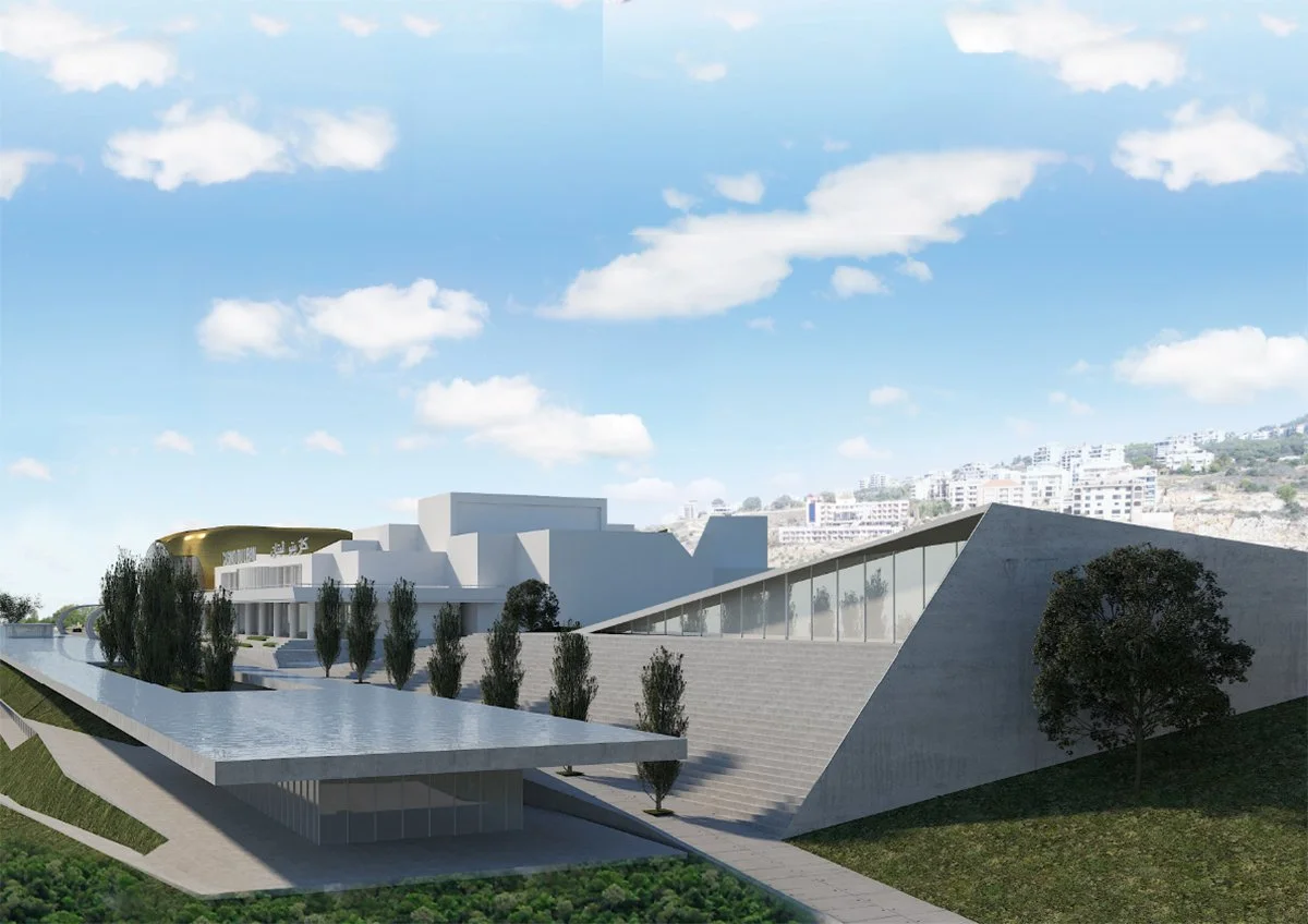 Modern architectural building with angular design, large glass windows, and steps leading up to it, surrounded by trees and a water feature, with a hillside and residential buildings in the background.