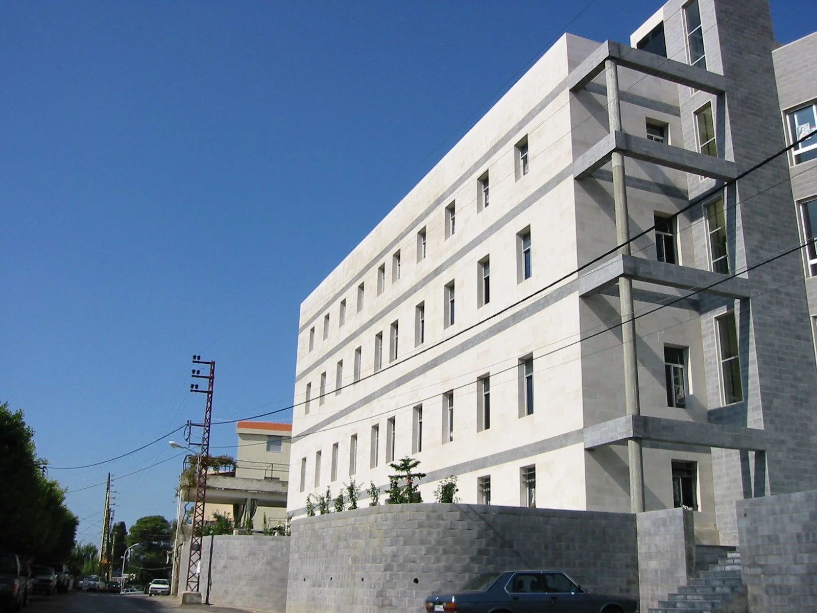 Modern multi-story residential building with gray and white exterior against a clear blue sky.