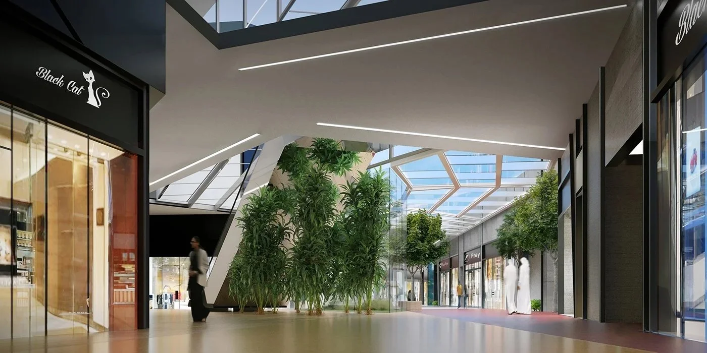 Interior view of a modern shopping mall with glass ceilings, greenery, and several shops including a store labeled Frey.