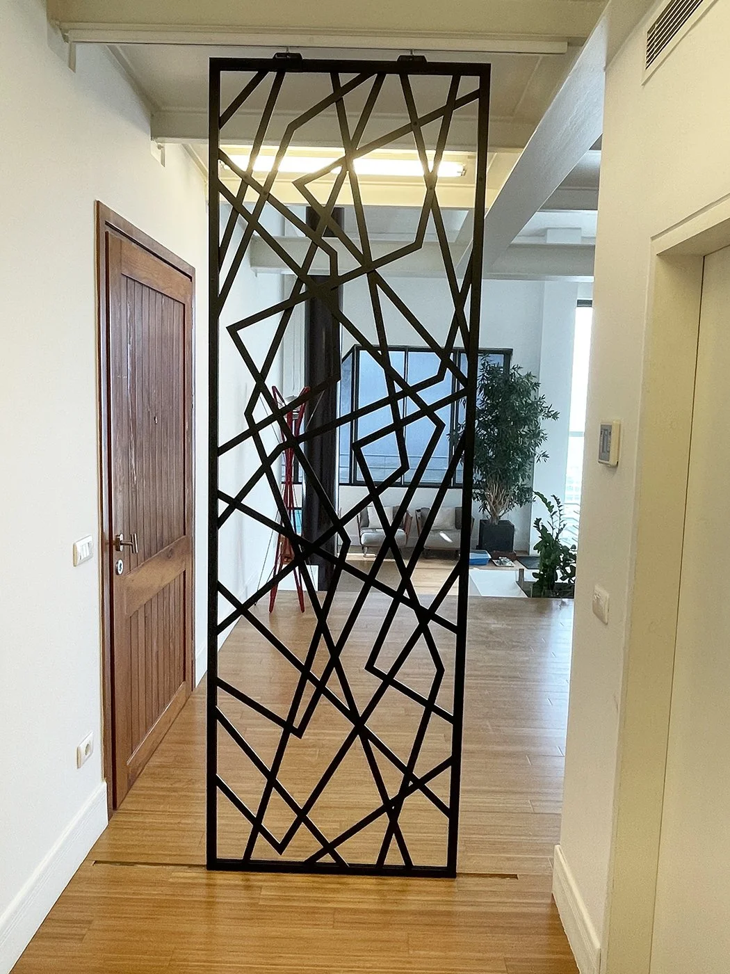 Decorative black metal room divider with abstract geometric pattern in a modern home interior.