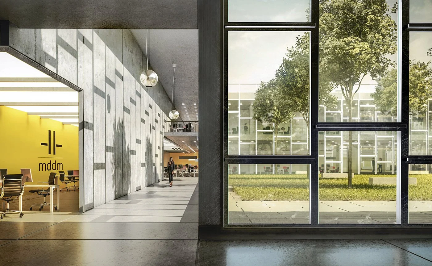 Modern office interior with a large glass window showing outdoor trees and grass, and a lobby area with a yellow wall and furniture.