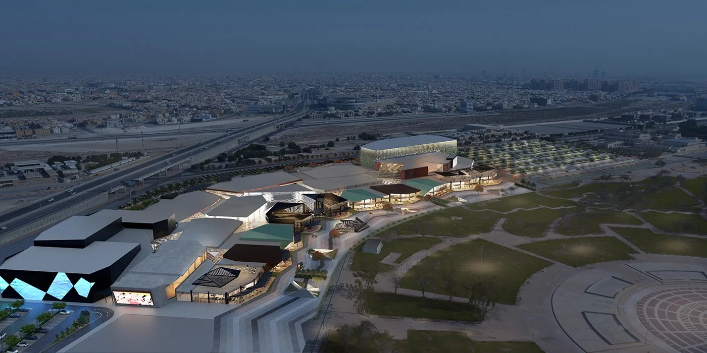 Aerial view of a modern urban development with multiple buildings, green spaces, and a highway, at dusk.