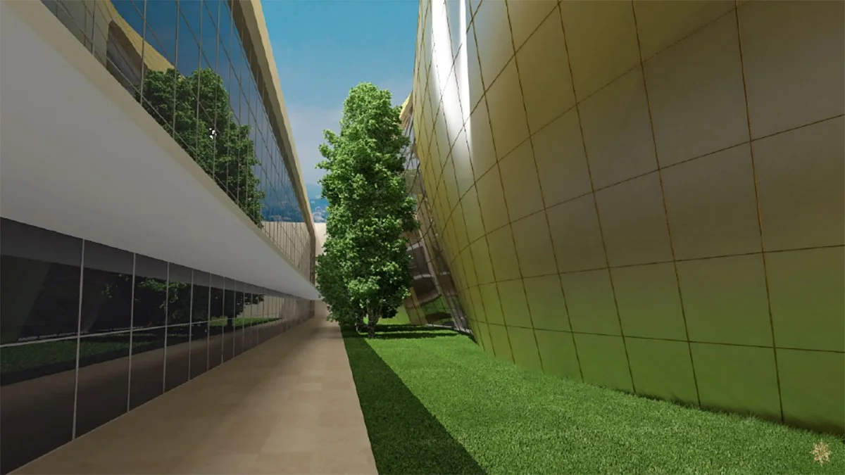 Modern building exterior with reflective glass windows, a green tree in the center, and an angled metallic gold-colored wall on the right side, with a tiled walkway and grass.