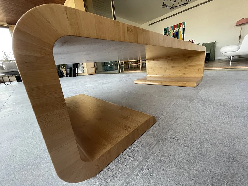 A modern wooden bench with a curved design located in a contemporary living room.