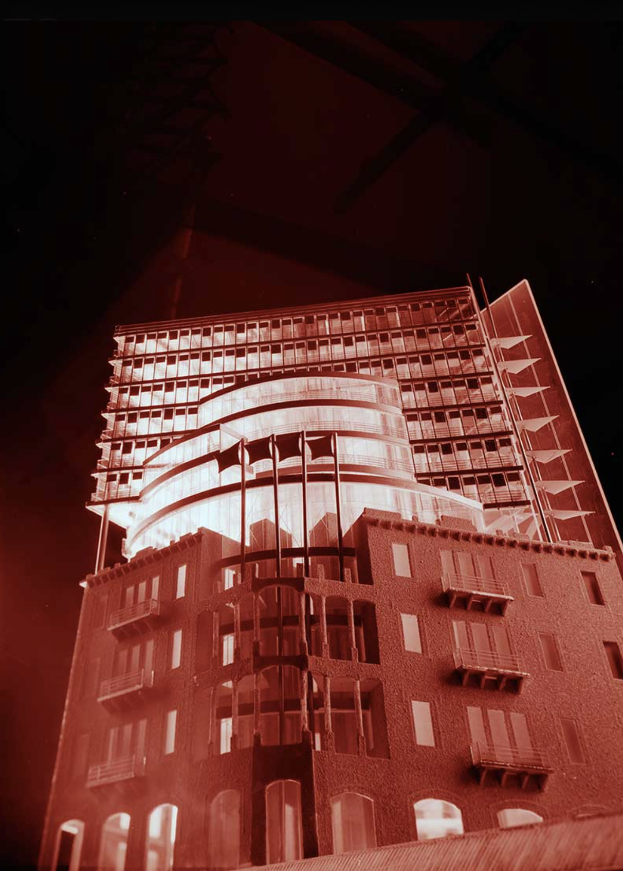 Night view of a modern multi-story building illuminated with red lighting against dark sky.