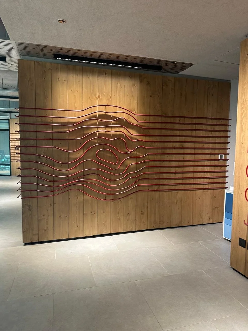 Decorative wall with wavy horizontal red lines on a wooden background.