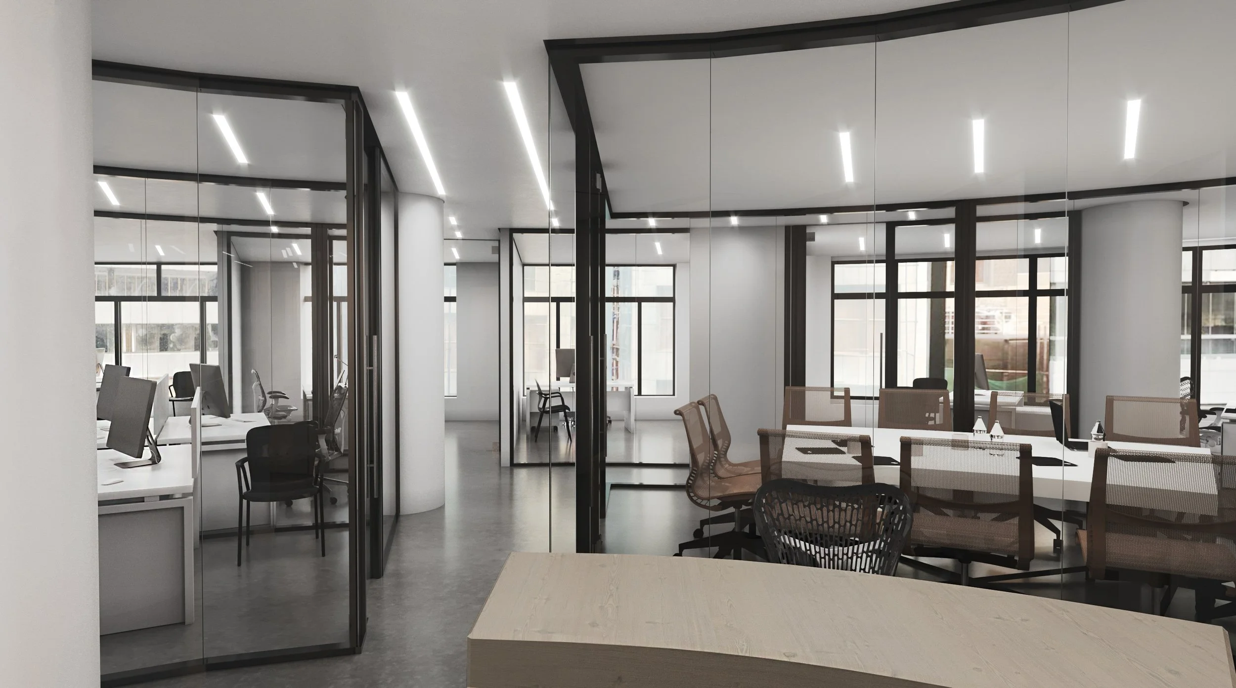 Modern open-plan office with glass partitions, workstations with desktop computers, office chairs, and large windows letting in natural light.