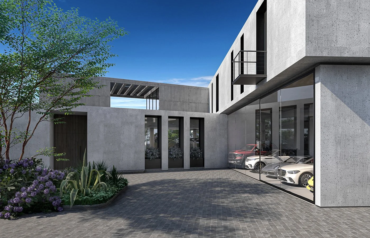 Modern concrete building with large glass windows showcasing cars inside, greenery and flowers in the front yard, and a blue sky overhead.