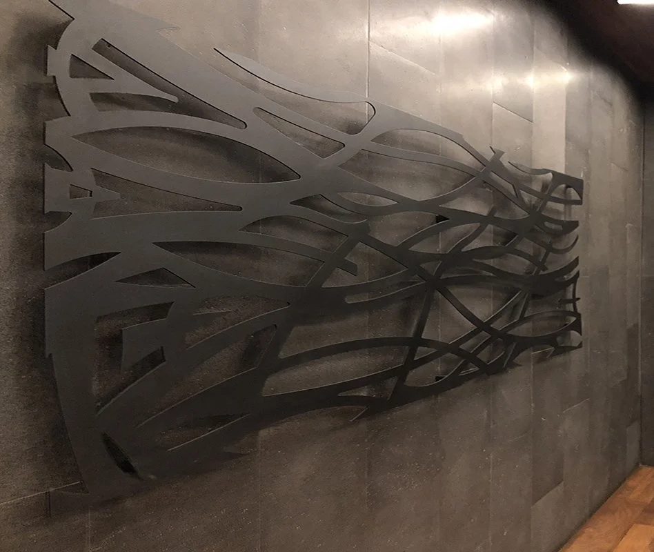 Decorative metal panel with an abstract, leaf-like design on a tiled wall.