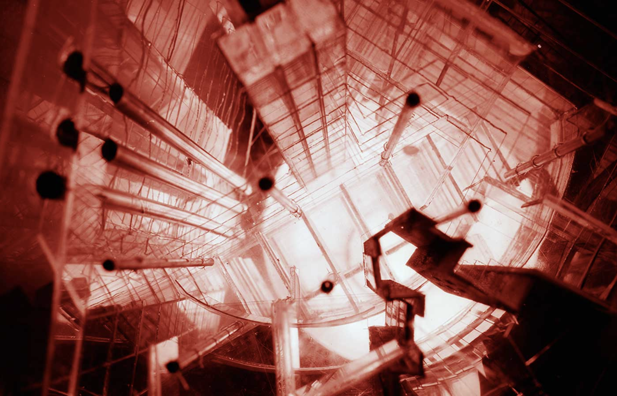 A laboratory with glassware and scientific equipment, illuminated with red light, viewed from below.