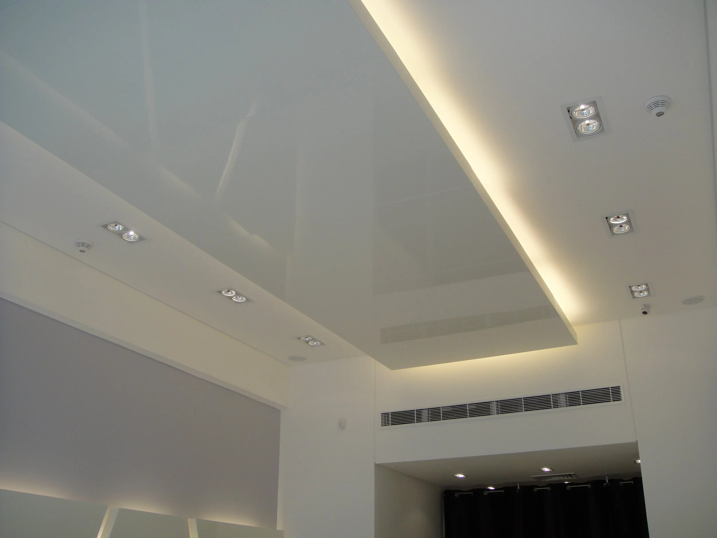 Ceiling with built-in lights and an air vent in a modern interior space.