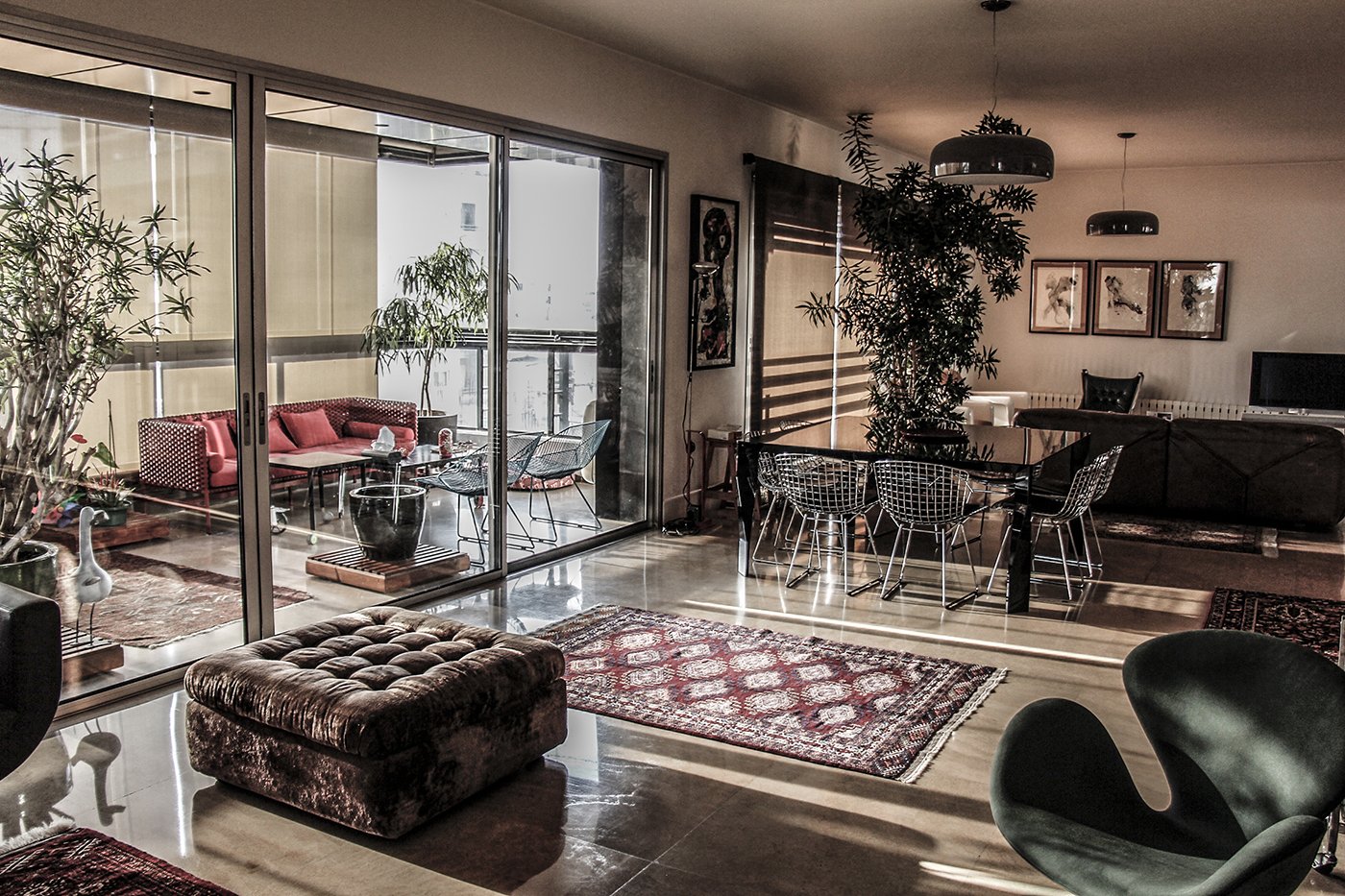 Living room with large glass doors leading to a balcony, decorated with modern furniture, plants, and framed artwork.