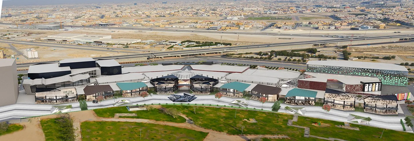An aerial rendering of a large outdoor shopping mall with multiple stores, walkways, seating areas, and green spaces, near a highway and urban area.