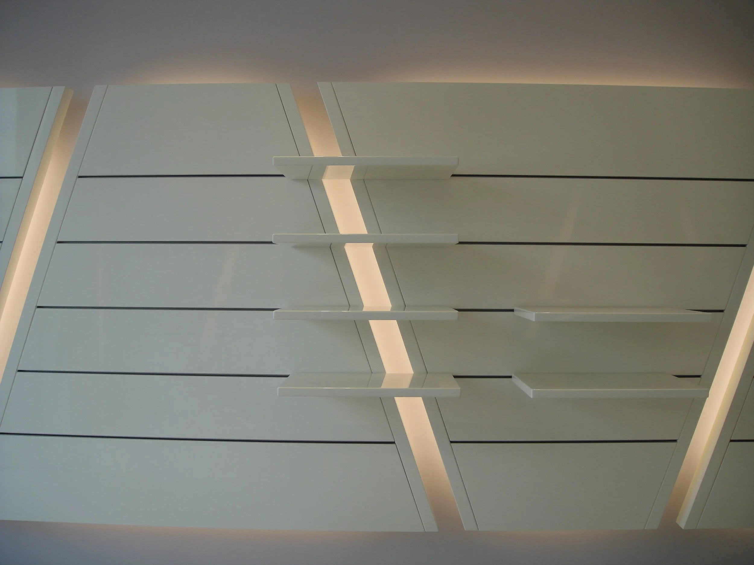 Close-up of a modern, minimalist white cabinet with horizontal handles, illuminated by soft lighting from above.