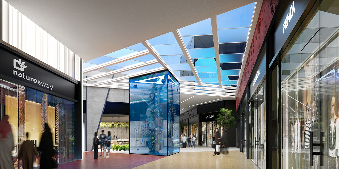 Modern shopping mall interior with storefronts labeled 'Nature's Way' and 'Fendi', a large glass display case, and people walking.