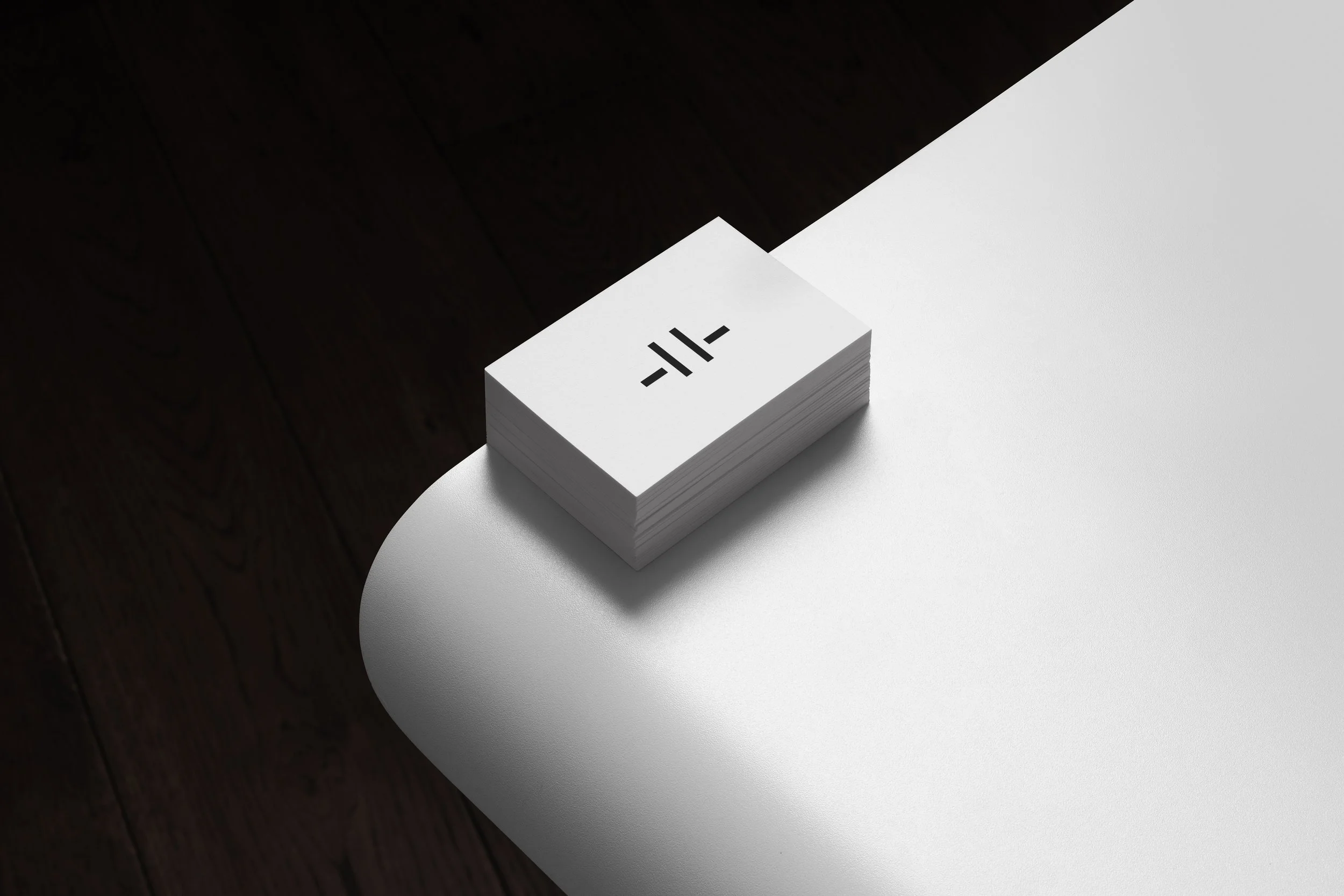 Stack of white cards with black symbols on a white table, with dark wood floor in the background.