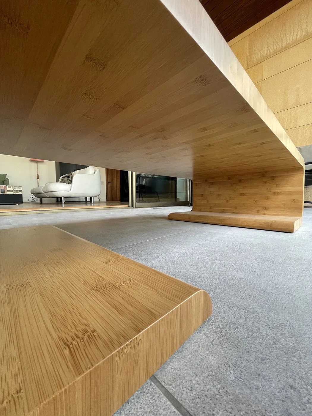Close-up view of a wooden table underside with modern furniture in the background.