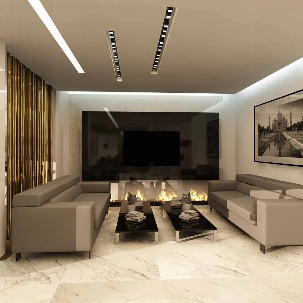 Modern living room with two gray sofas, black coffee tables with stacks of books and small potted plants, a fireplace with flames, a large flat-screen TV on the back wall, framed black-and-white photo of Taj Mahal, marble flooring, and contemporary c